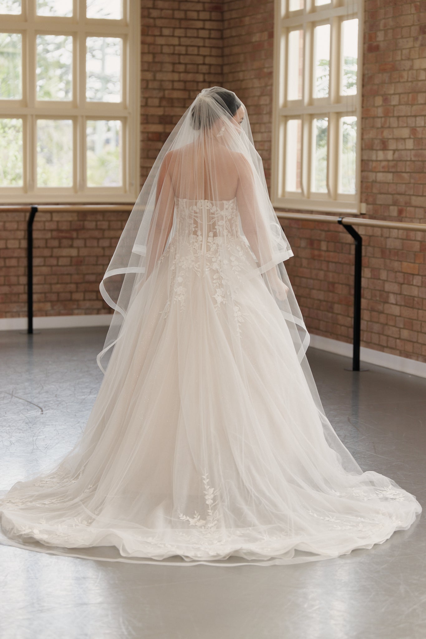 Back view of the Camille bridal gown showcasing medium-length train and embroidered bodice and tulle skirt.