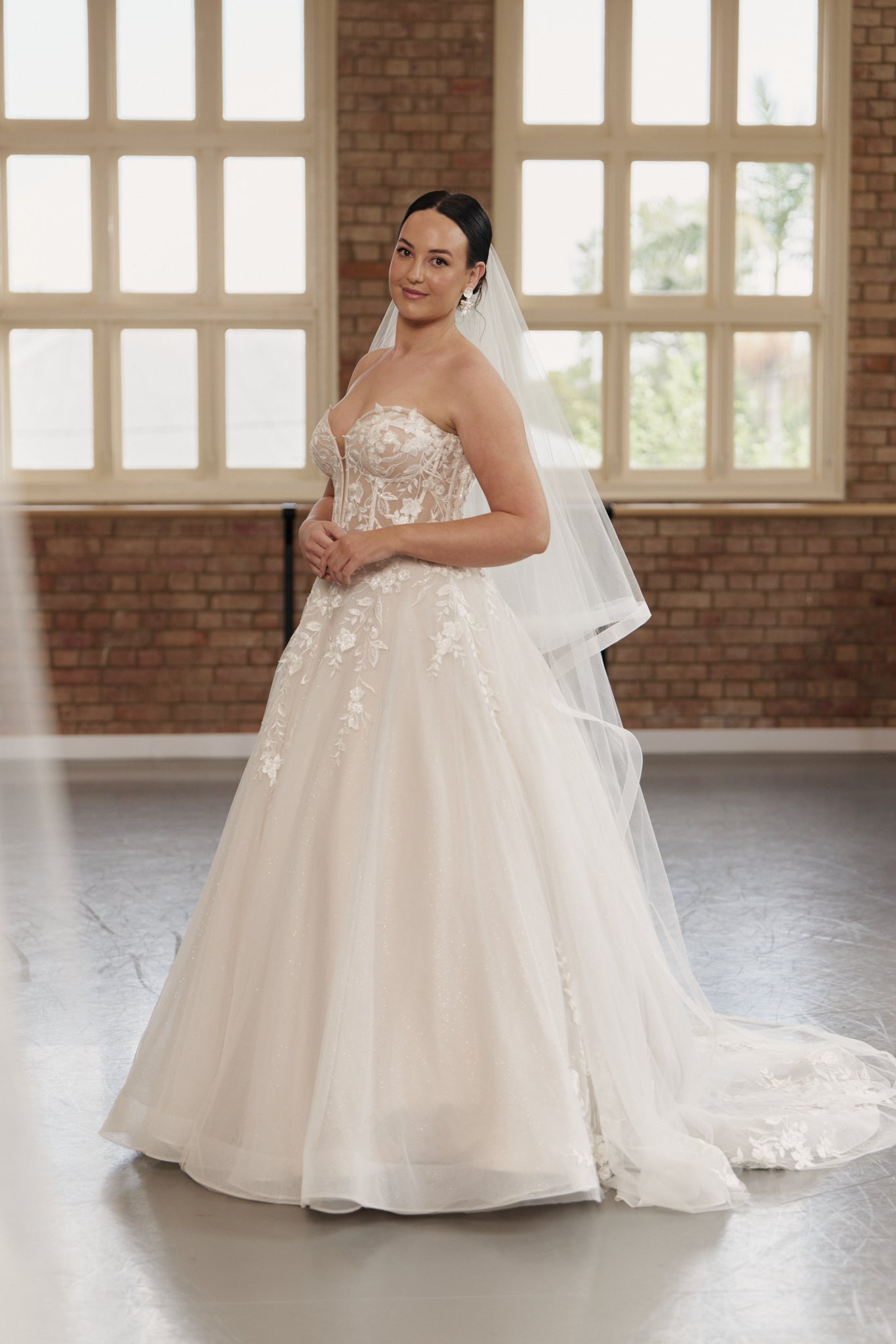 Elegant Camille strapless wedding gown with structured bodice, embroidered tulle princess skirt, and medium-length train.