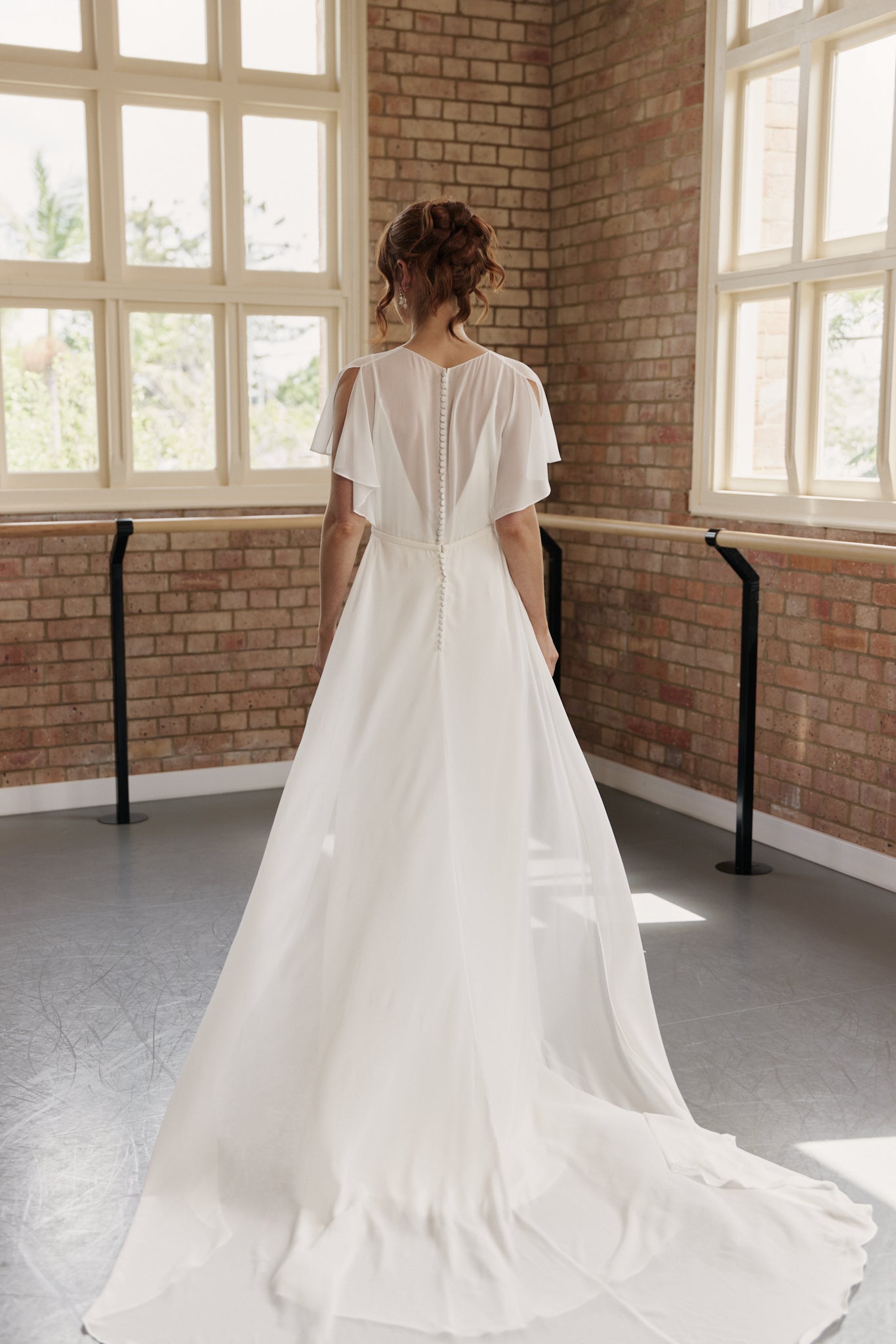 Back of Clare wedding dress showing A-line skirt with train and crossover bodice with flutter sleeves.
