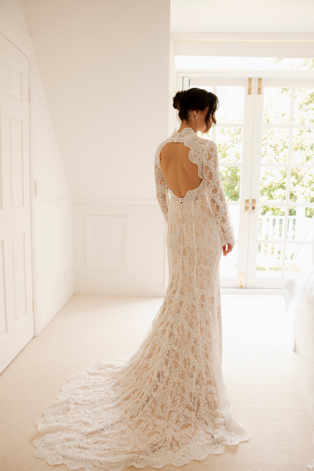 Jess wedding dress with long lace sleeves, high neckline, open back, and fitted silhouette with train
