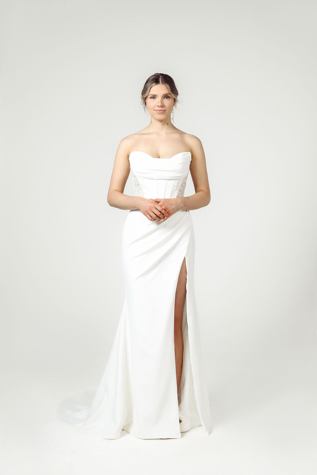 Front view of strapless wedding gown with ruched bodice, cat's eye neckline, exposed boning, beaded detailing, and optional off-the-shoulder sleeves.