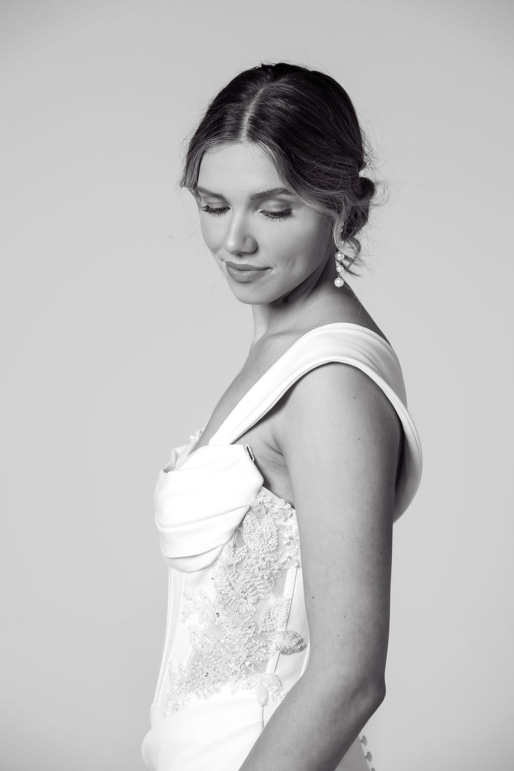Side profile of strapless dress highlighting ruched bodice, beaded detailing.