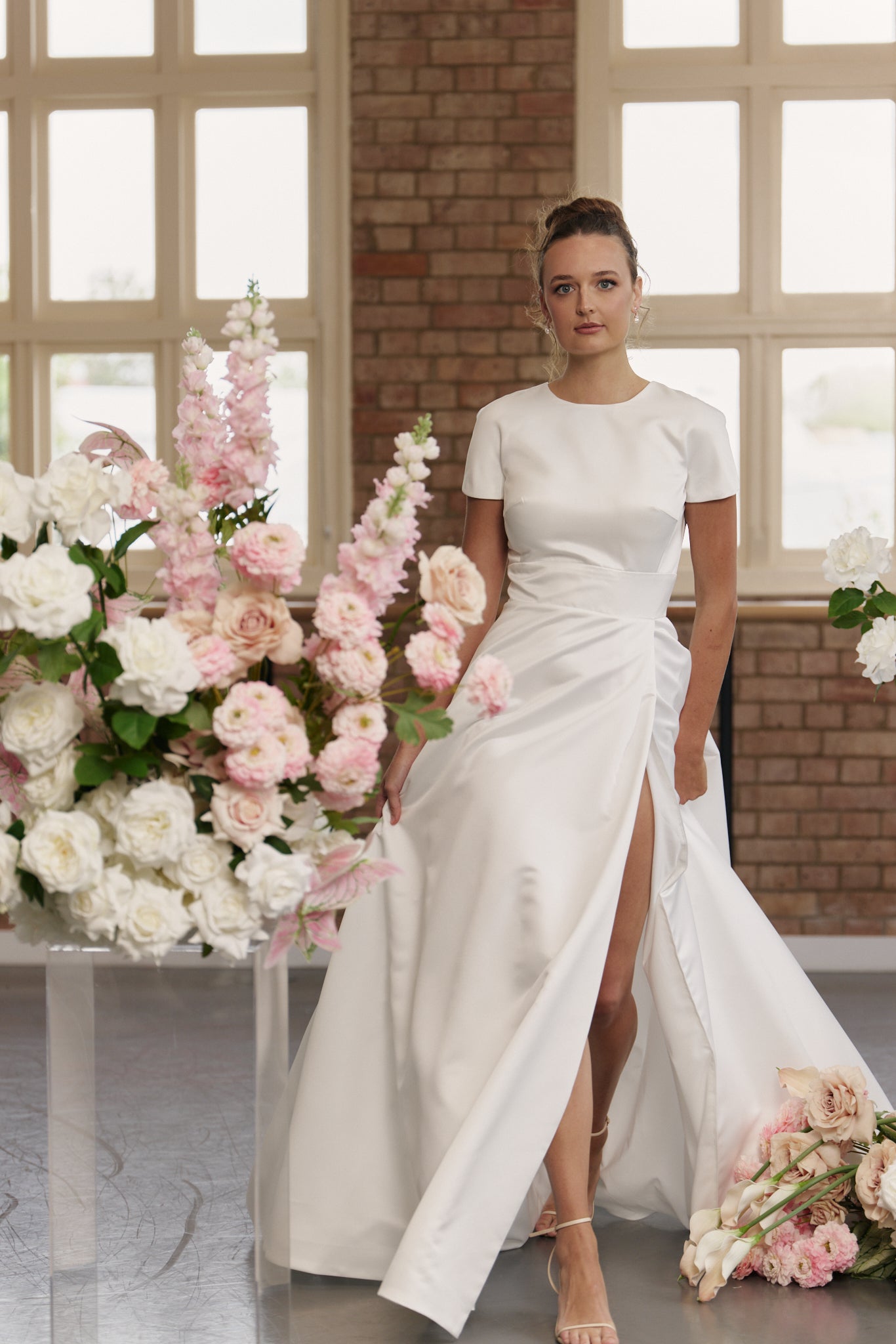 Bride wearing Jane wedding dress with short sleeves, round neckline, fitted waistband, and full skirt with split