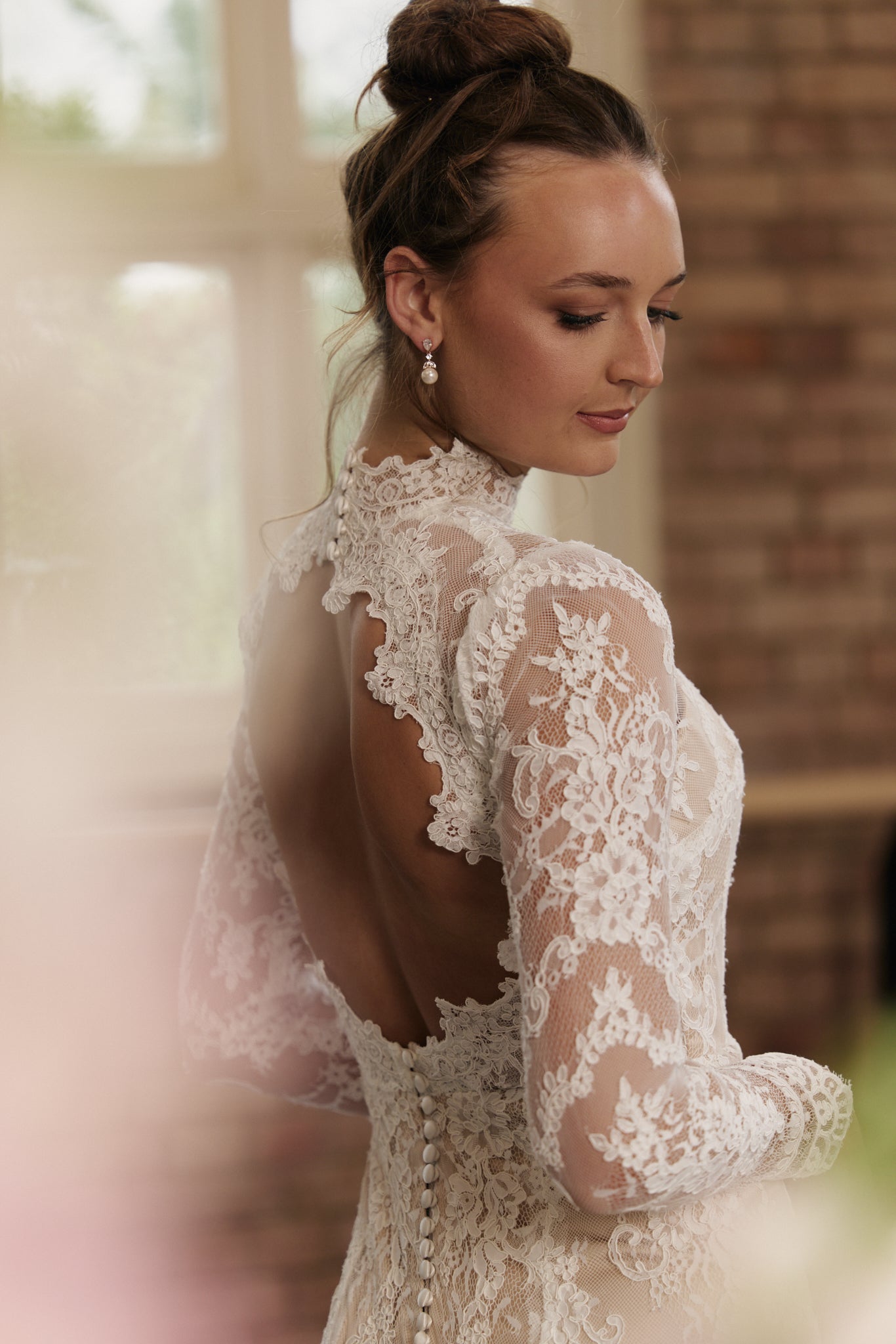 Back of lace sheath wedding dress with open back and long sleeves.