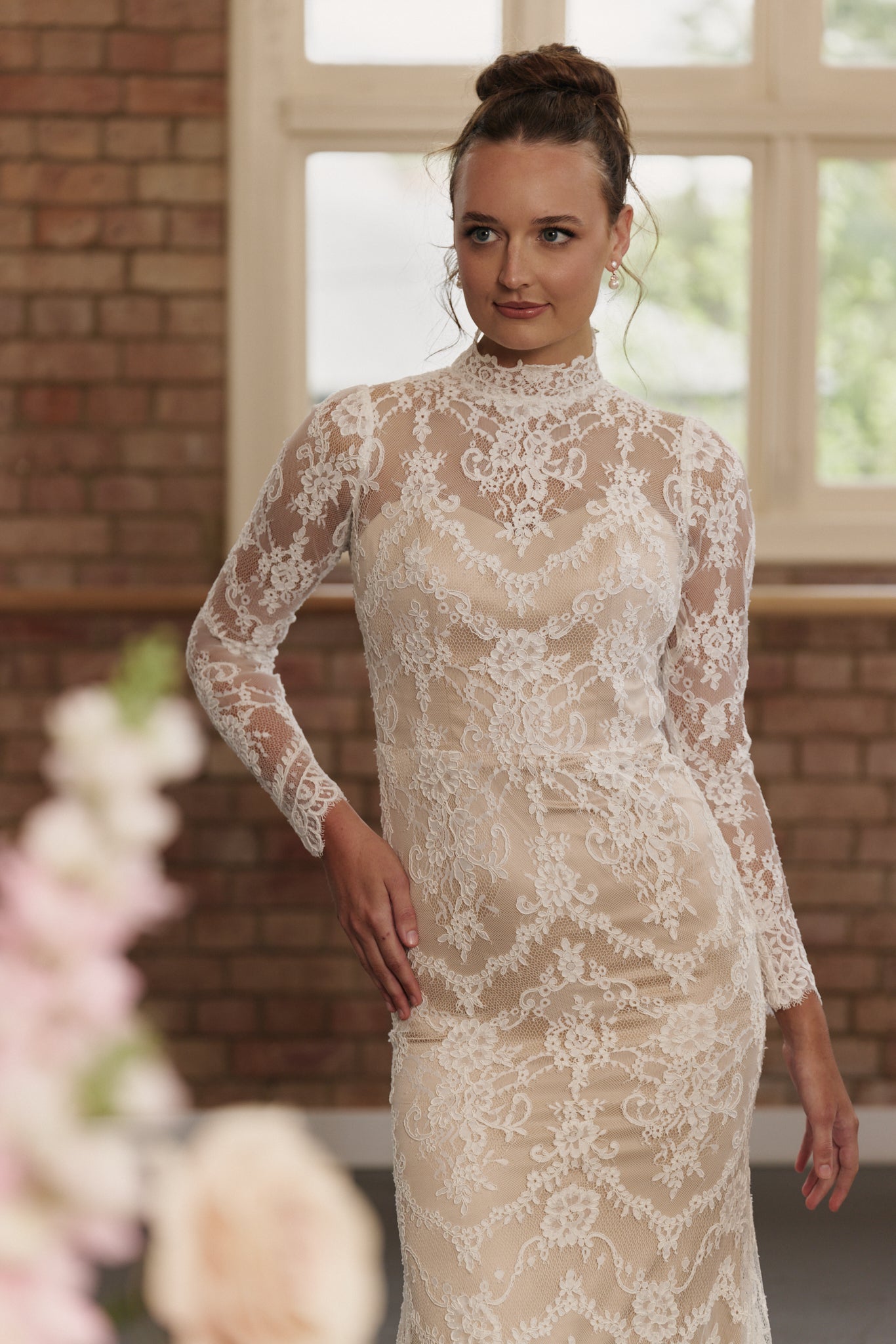 Close-up of high neckline and lace detailing on sheath wedding dress with long sleeves.