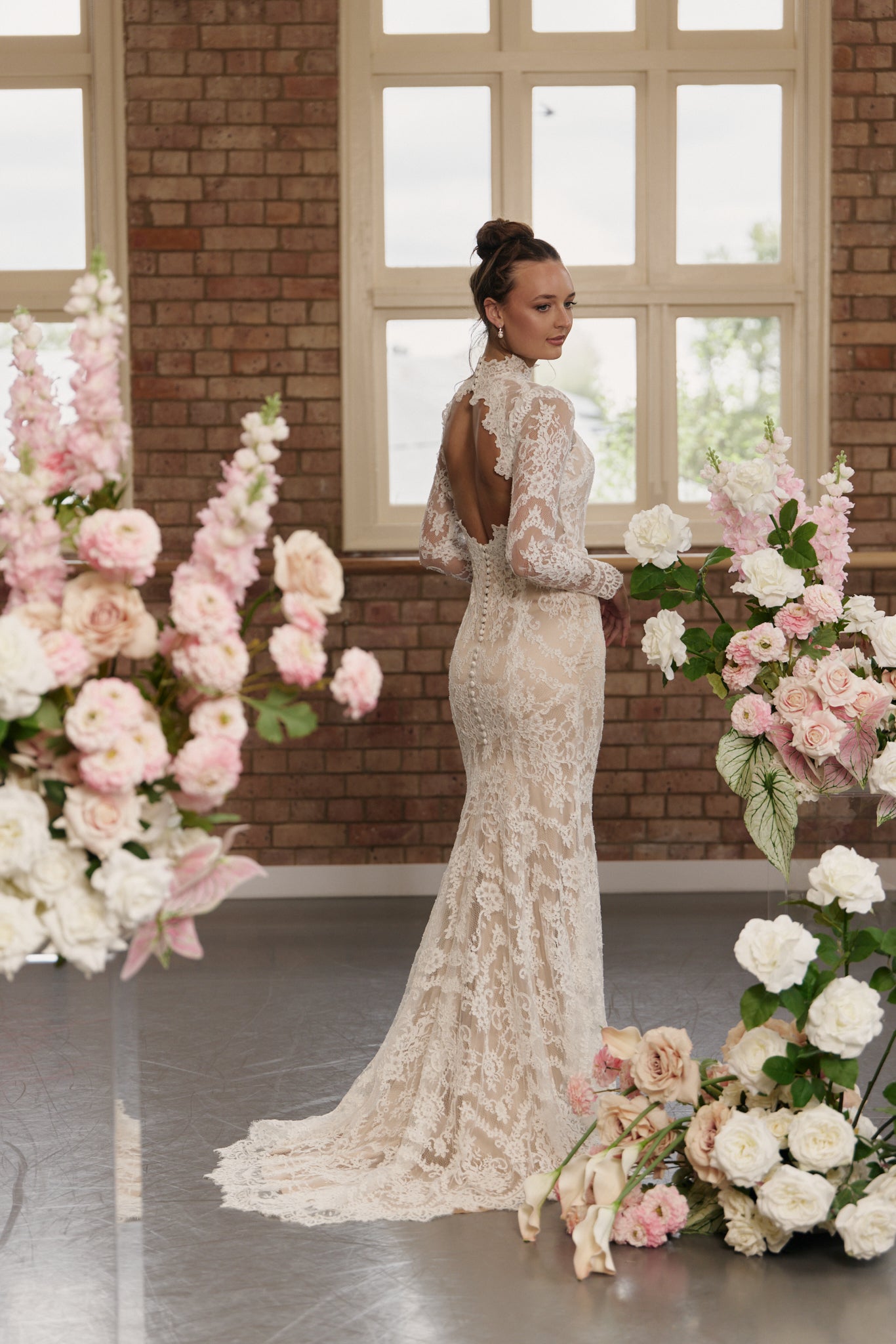 Back of lace sheath wedding gown with open back and long sleeves.