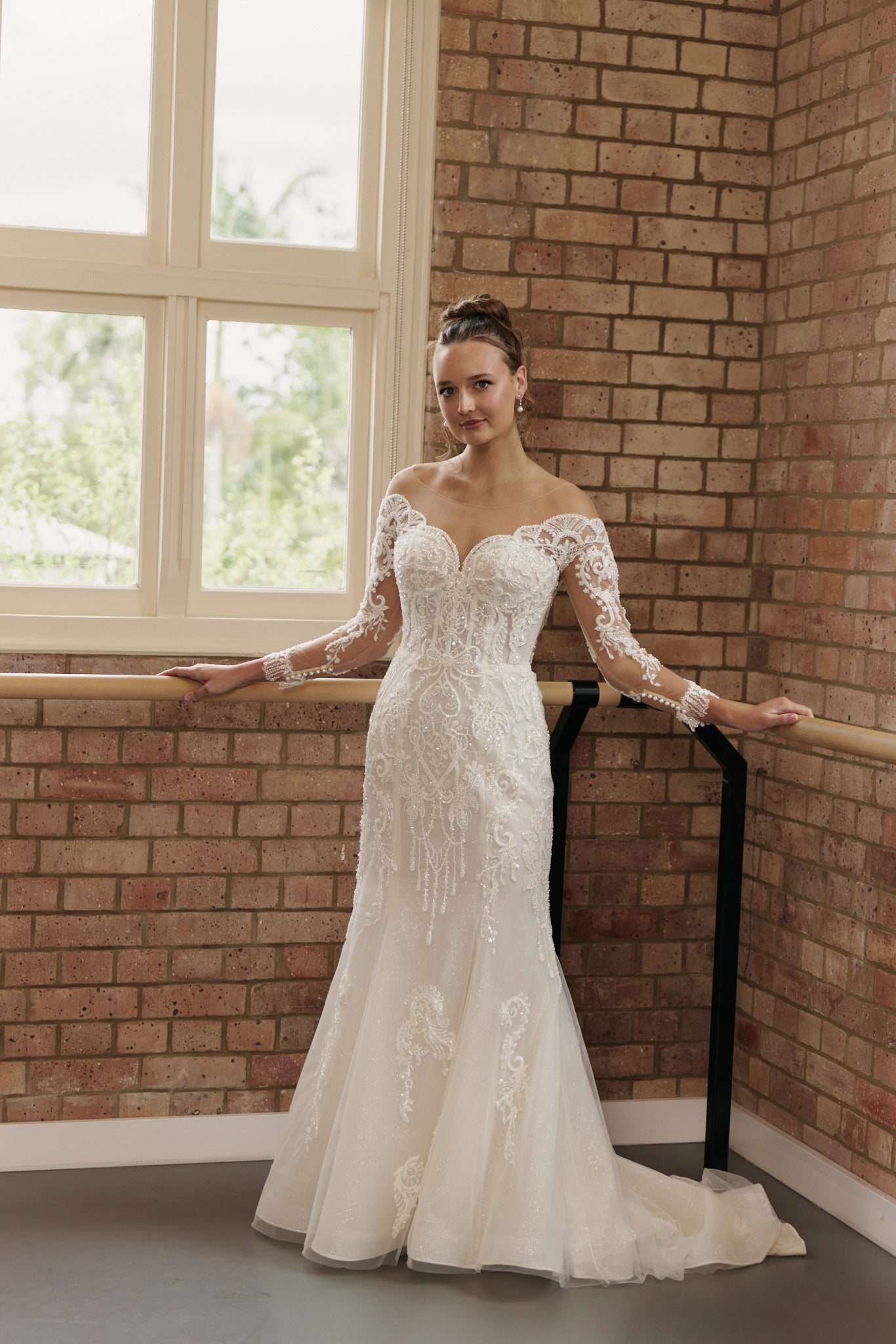Bride wearing Labelle wedding dress with off-shoulder, beaded sheer sleeves, lace bodice, and figure-flattering mermaid skirt.
