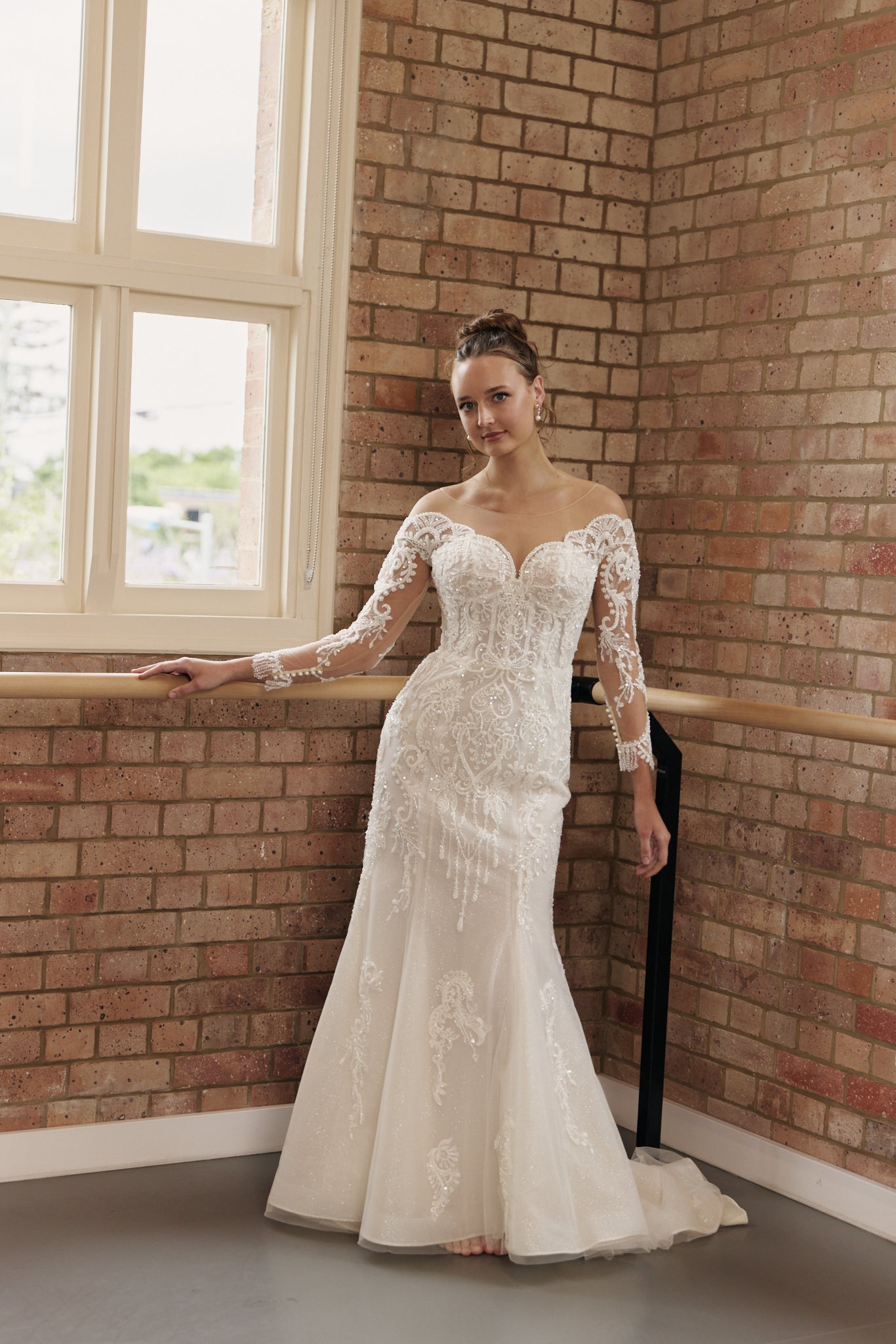 Bride wearing Labelle wedding gown with off-the-shoulder, beaded sheer sleeves, lace bodice, and figure-flattering mermaid skirt.