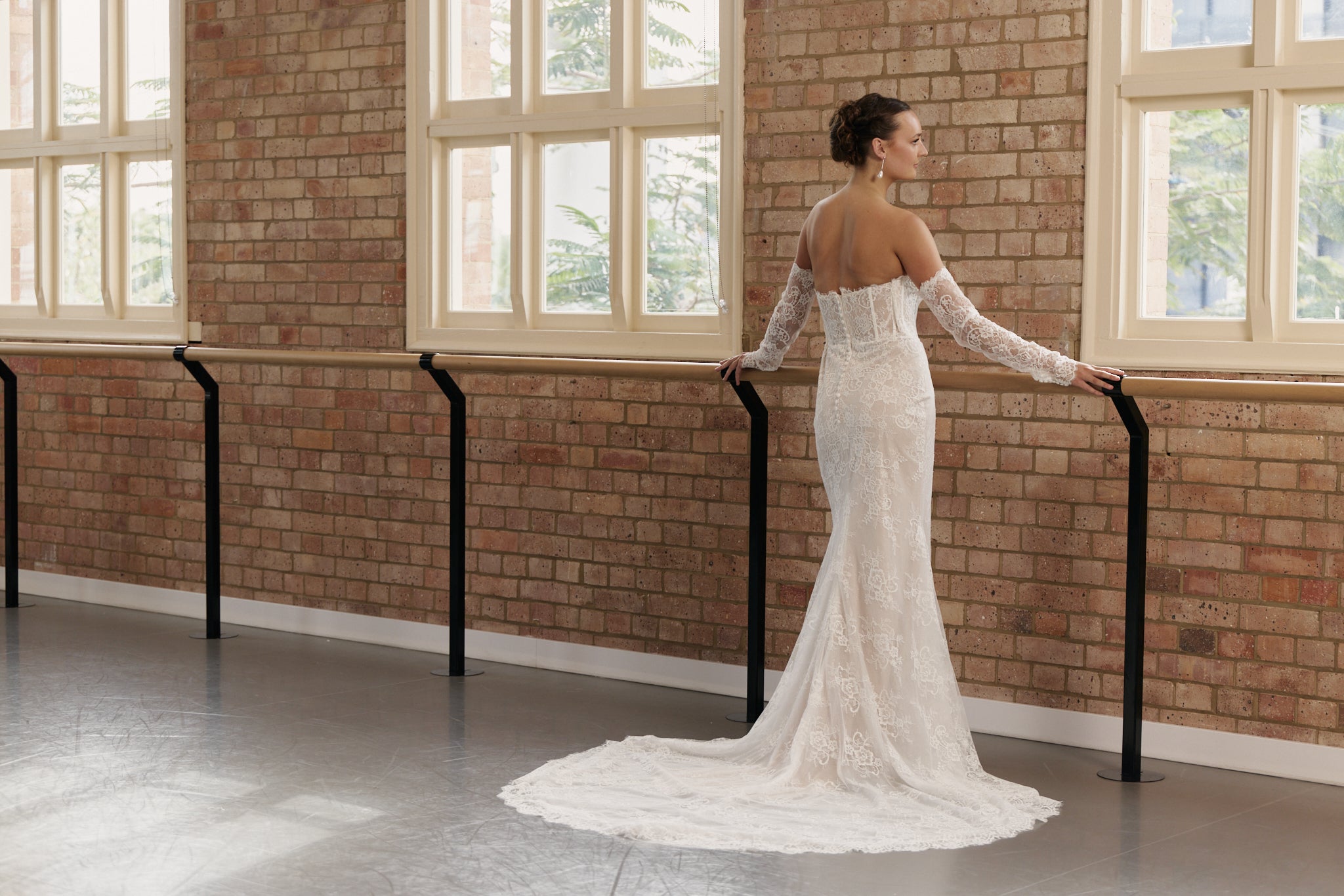 Full back view of off-the-shoulder lace wedding gown with clean design and figure-hugging mermaid skirt.