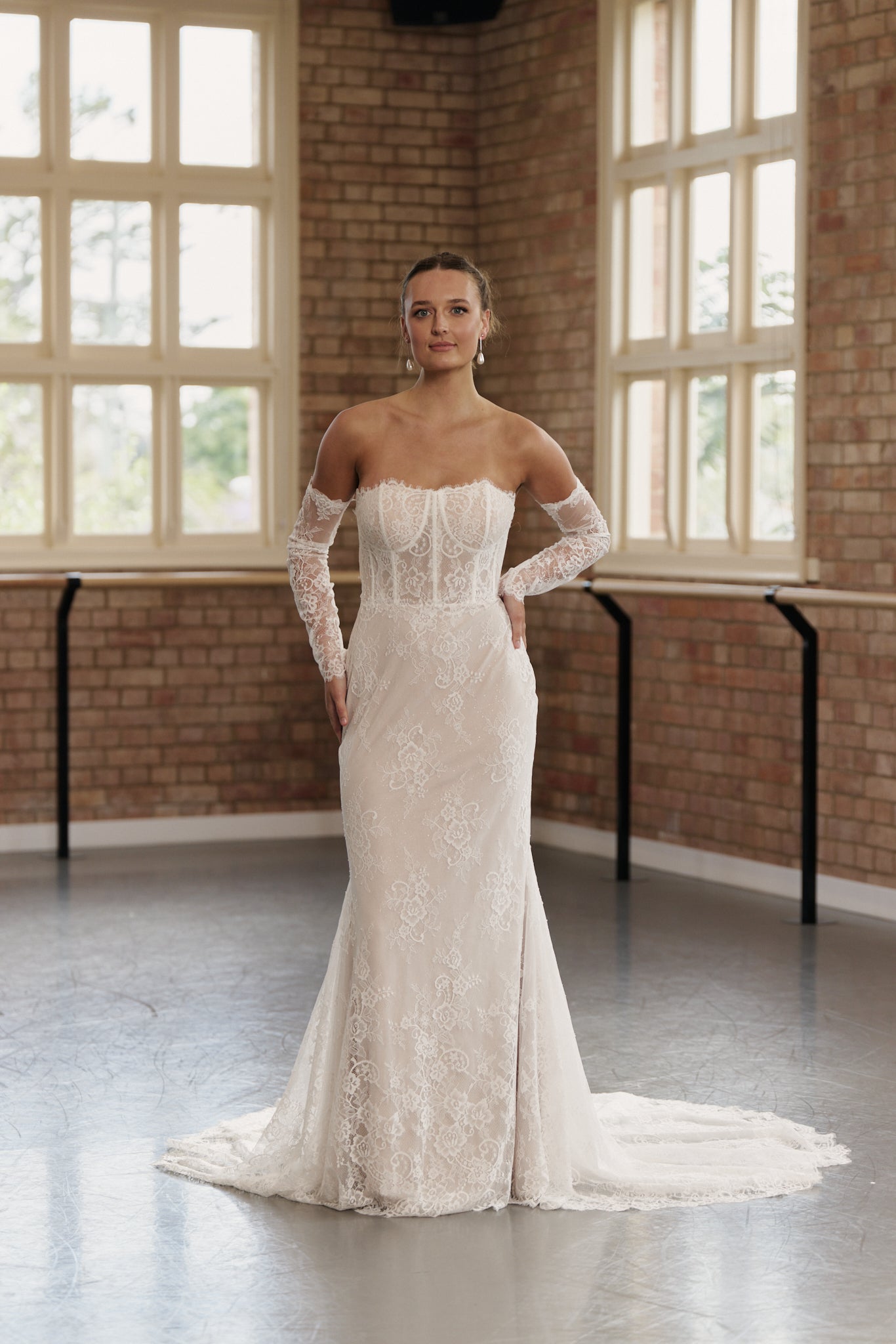 Off-the-shoulder lace wedding dress with long sleeves, structured corset bodice, and mermaid silhouette.