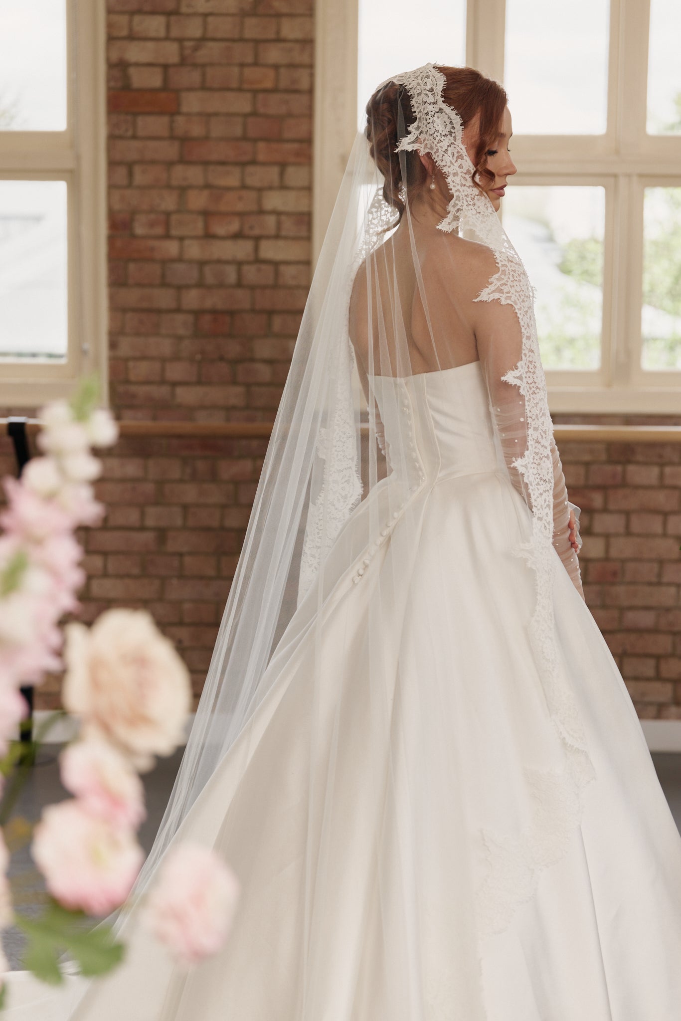 Back view of the Mackenzie bridal gown showing the button down bodice, basque waist detail, and flowing princess-style train