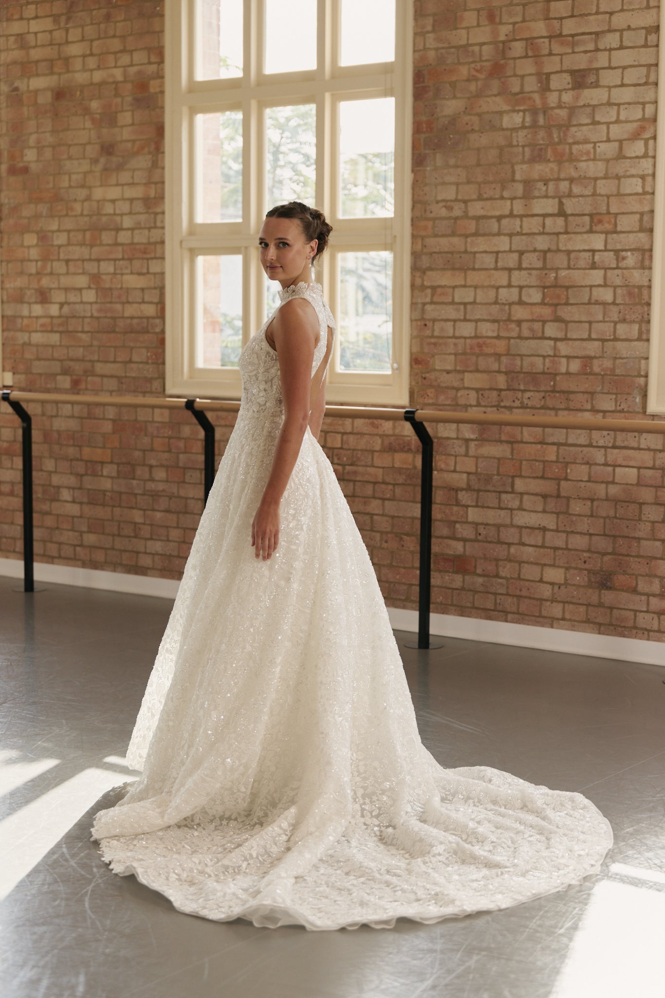 Side profile of the Mia wedding gown highlighting the fitted beaded bodice, cutaway halter neckline, and flowing full skirt.