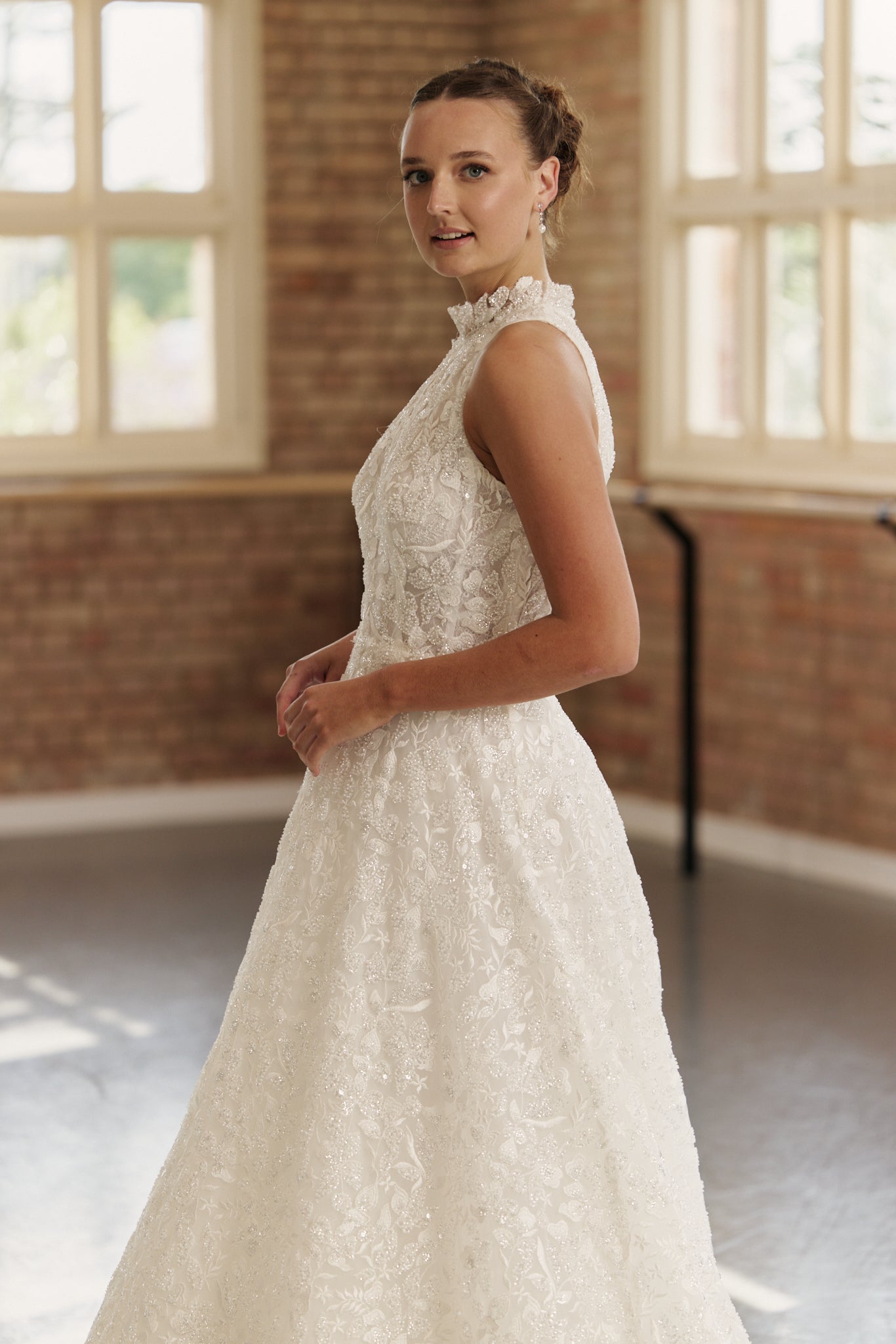 Side profile of the Mia wedding dress highlighting the fitted beaded bodice, cutaway halter neckline, and flowing full skirt.