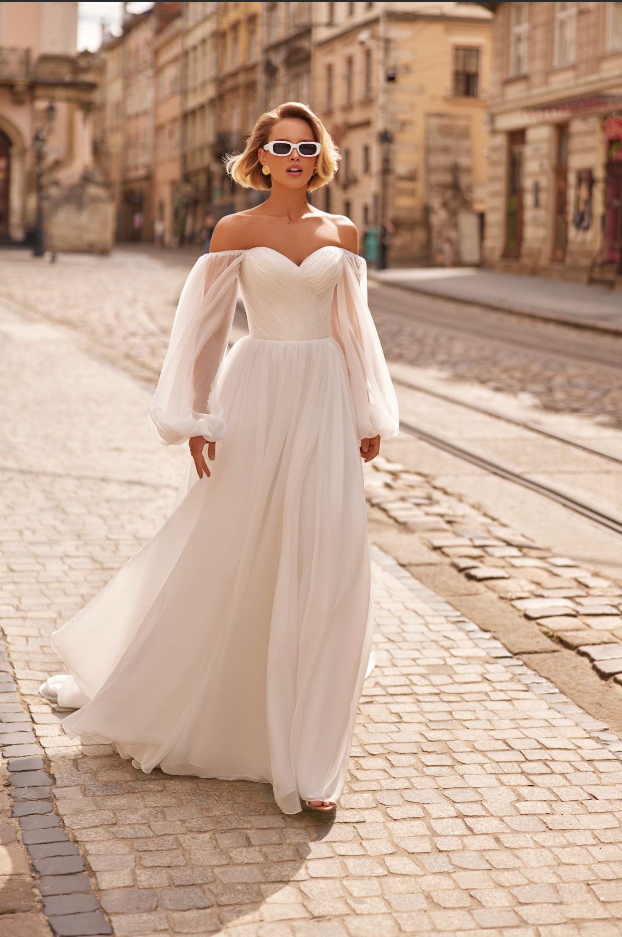 Petra Wedding Gown, Corset bodice, a line silhouette, draped ing light chiffon fabric, strapless with billowy chiffon sleeves.