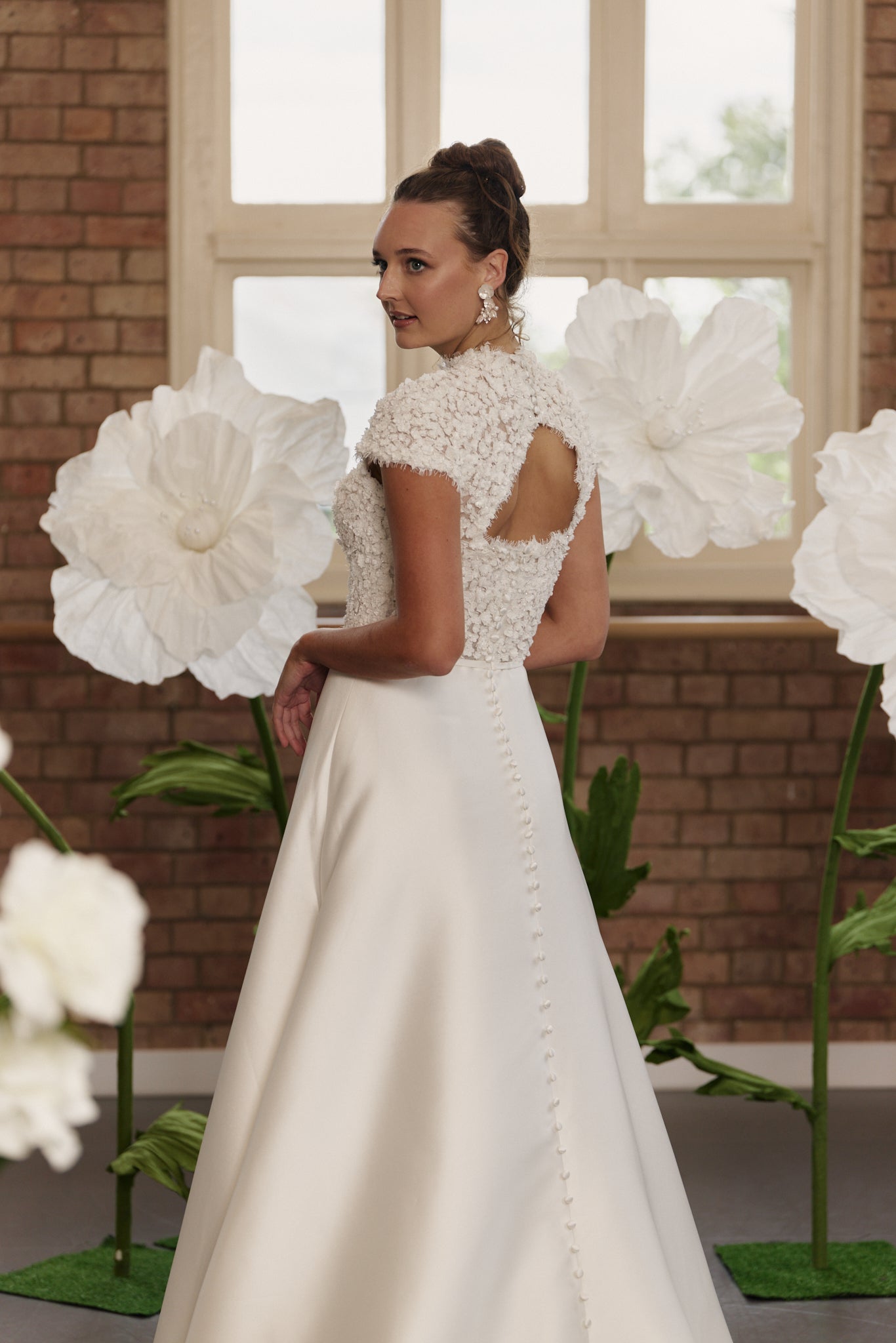 Back view of Pippa wedding dress showing open back trimmed with scalloped lace and buttons, with delicate waistband and a-line skirt.