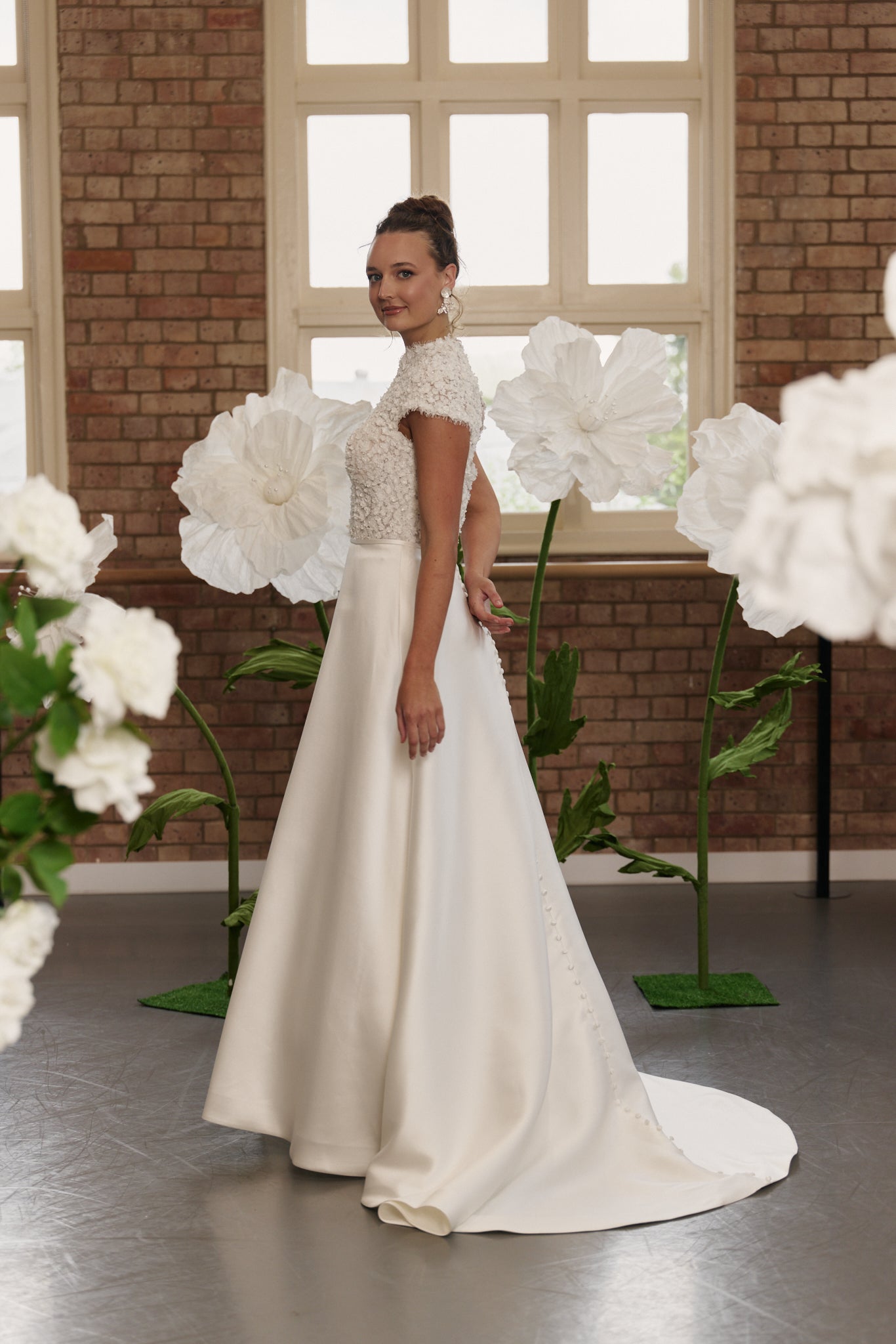 Side profile of classic wedding dress highlighting floral lace bodice, high neckline, cap sleeves, and elegant A-line silhouette.
