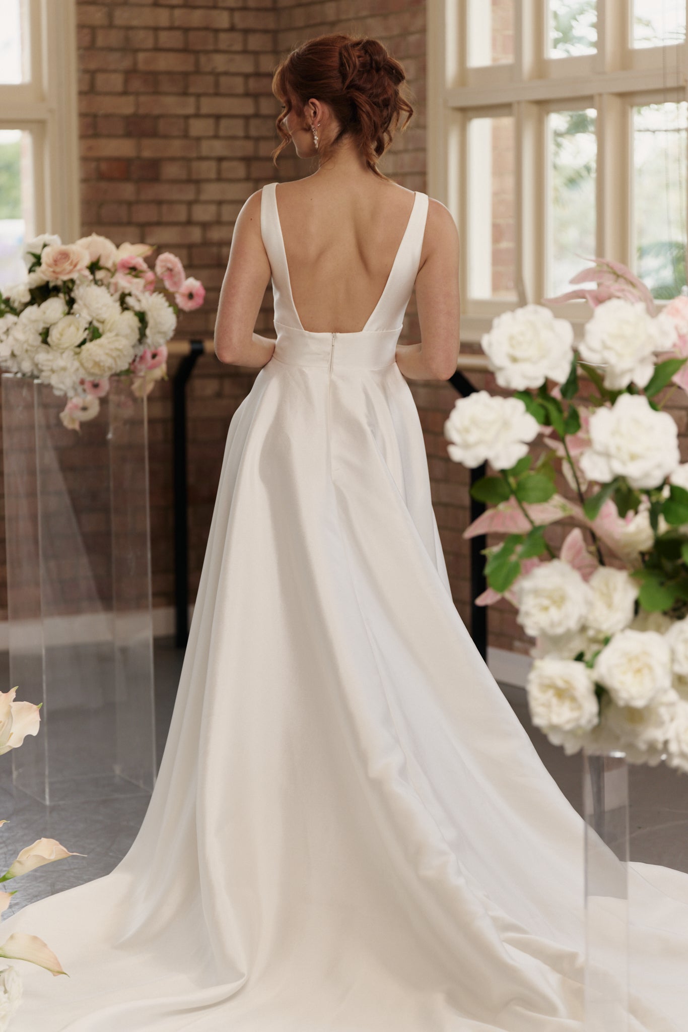 Back view of the Rachel bridal gown showcasing open back, flowing train and clean, minimal design.