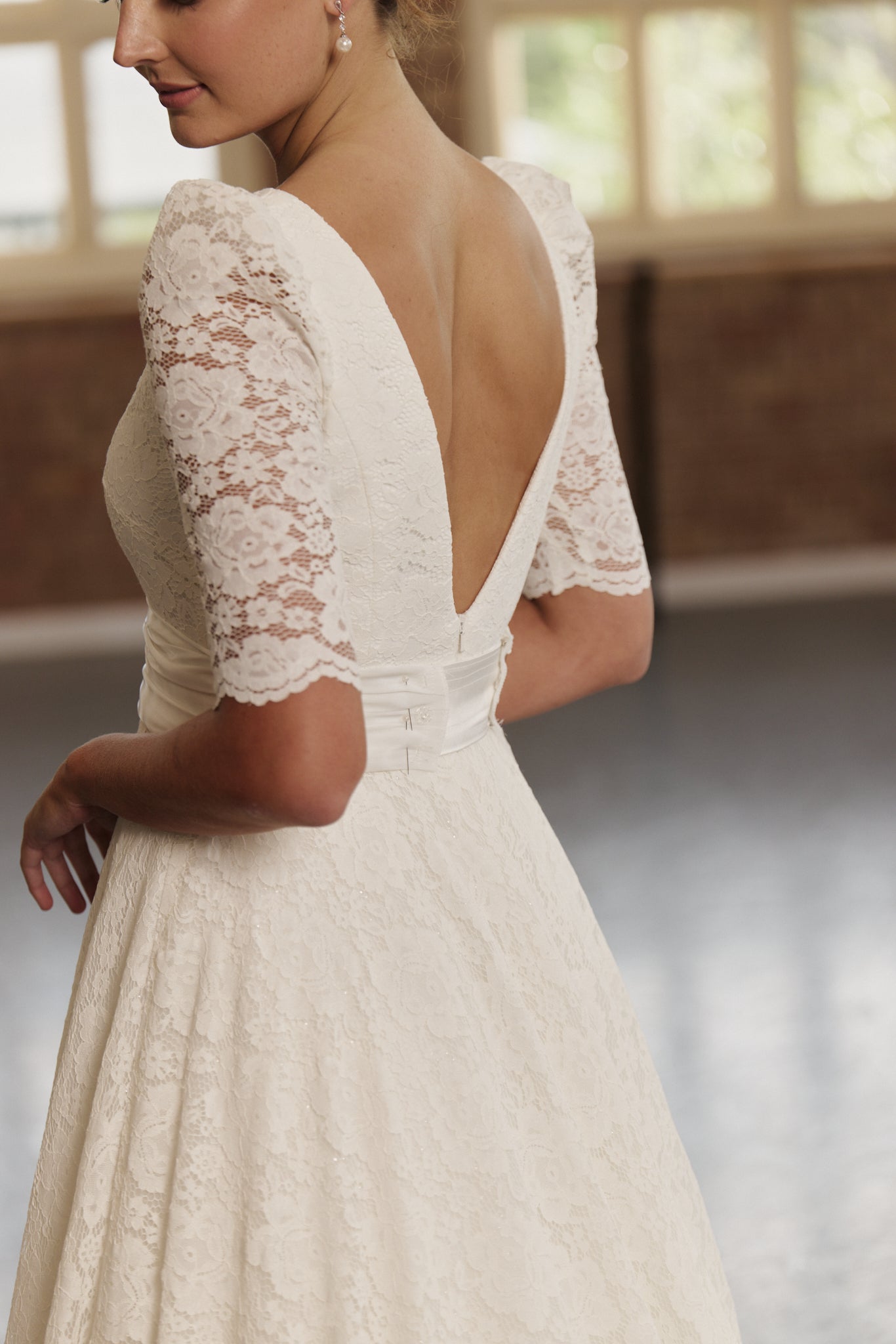 Roma bridal gown in full lace featuring soft boat neckline, cinched silk waistband, and feminine A-line silhouette