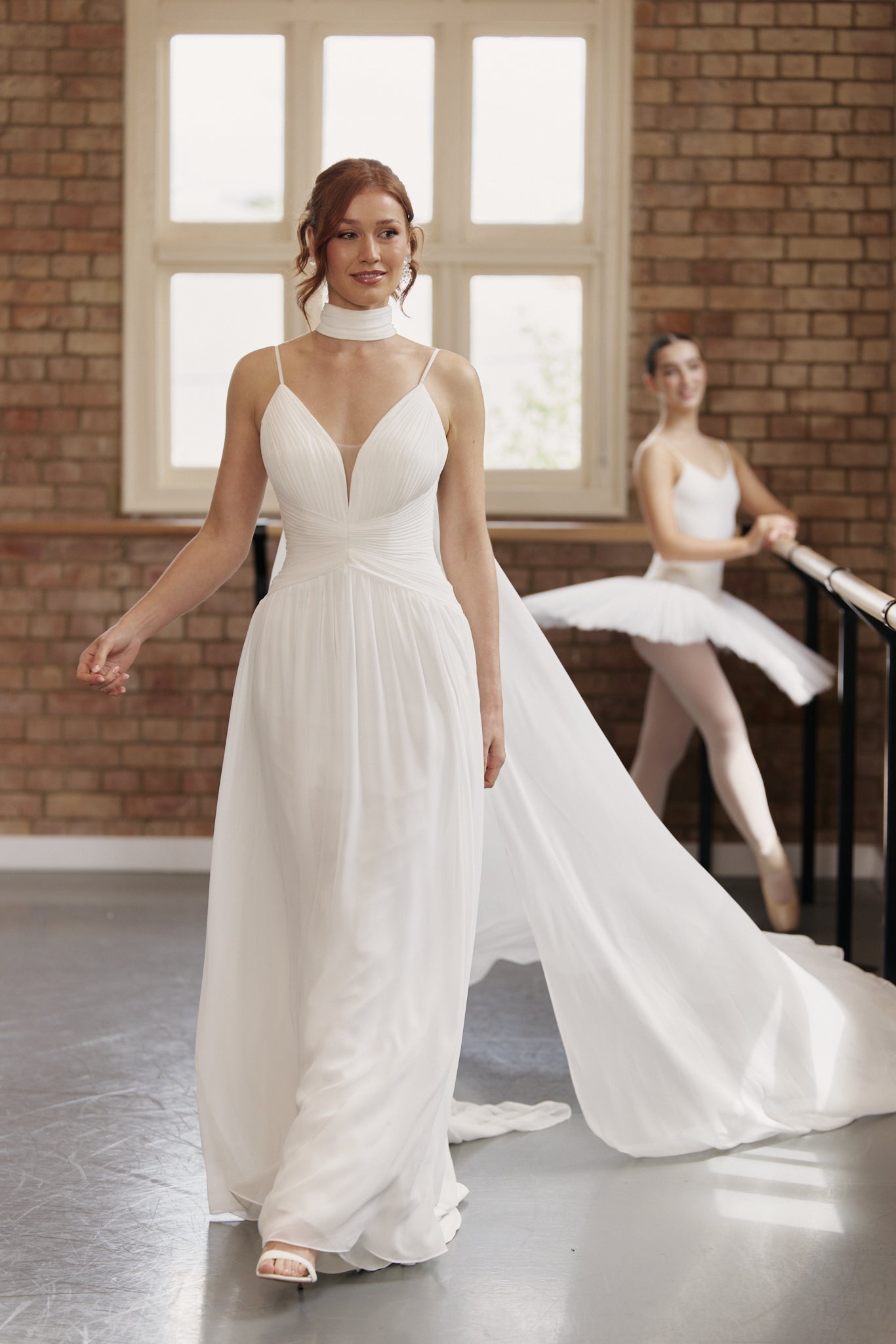 Bride wearing chiffon neck scarf with soft collar and flowing panels instead of a veil.