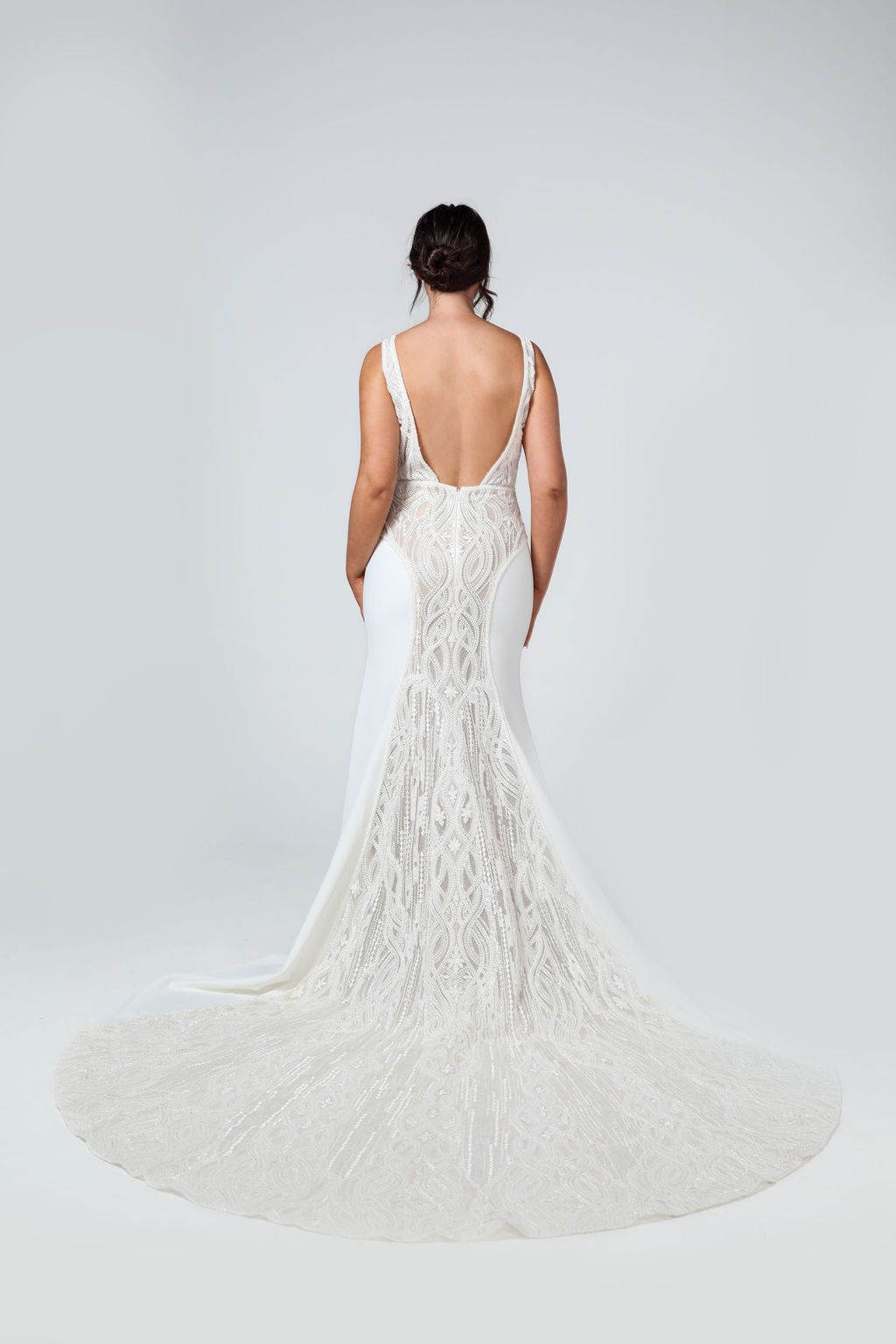 Back view of the Valentina bridal gown showcasing flowing train and intricate beaded geometric detailing.