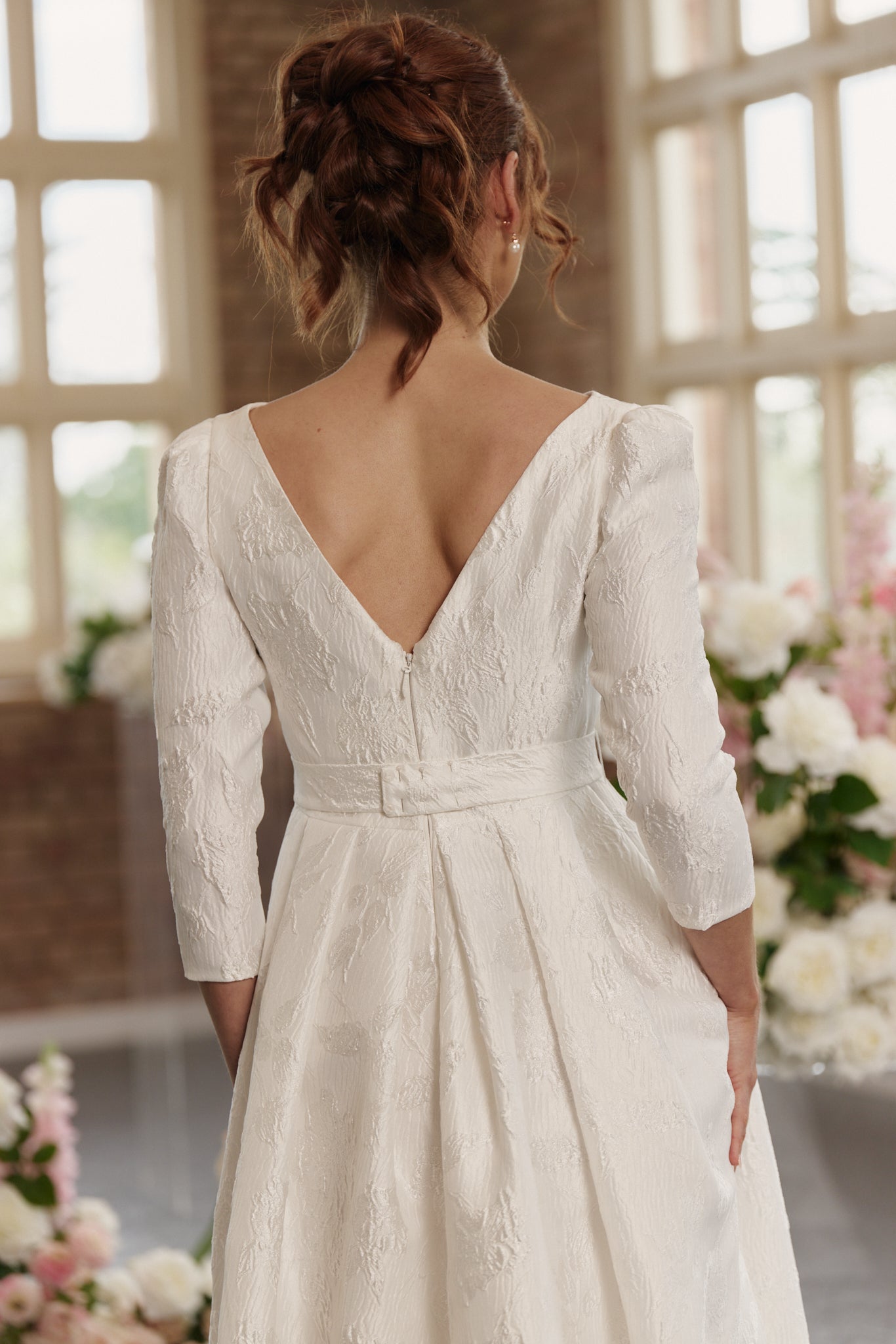 Andrea Wedding Dress with boat neck, 3/4 long sleeves, hi lo hemline, in jacquard, showing V-back close up