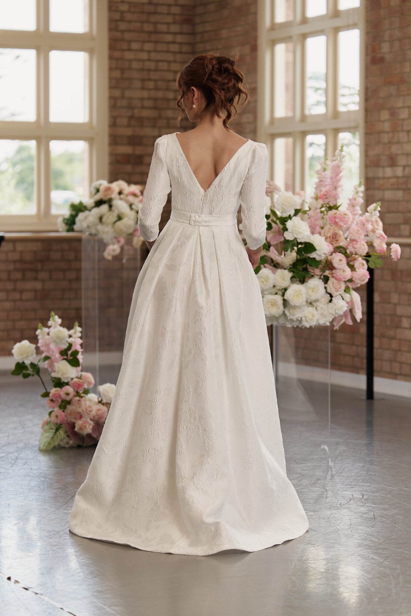 Andrea Wedding Dress with boat neck, 3/4 long sleeves, hi lo hemline, in jacquard, with low V back.