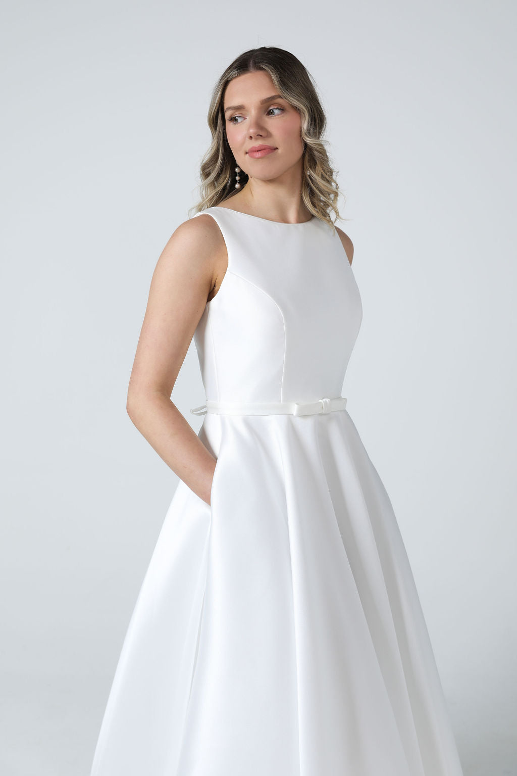 Front view of elegant boat-neck wedding dress in glossy satin Mikado with a cinched waist and full princess skirt