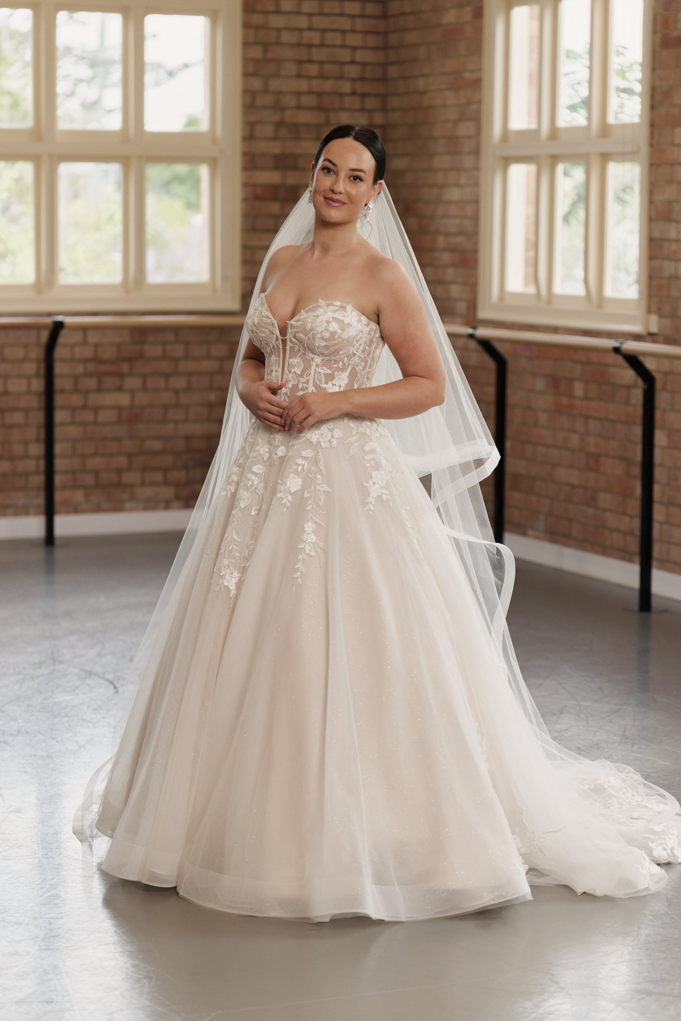 Front view of the Camille strapless wedding gown with structured bodice and embroidered flowing tulle princess-style skirt.