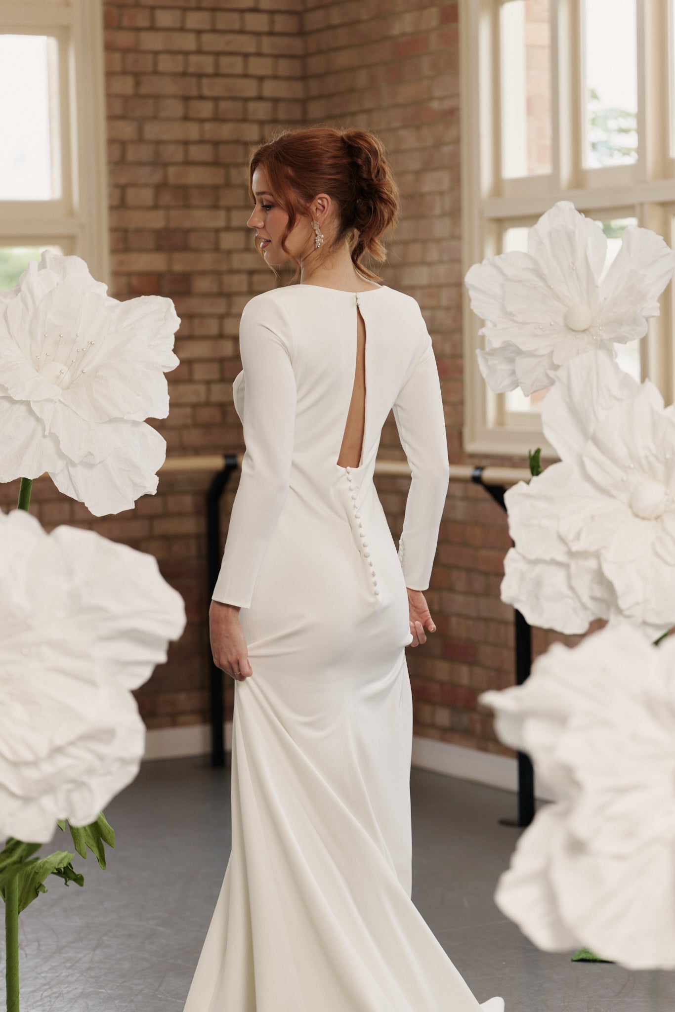 Back of Charlotte sheath wedding dress with open back, long sleeves, and square neckline in soft crepe.
