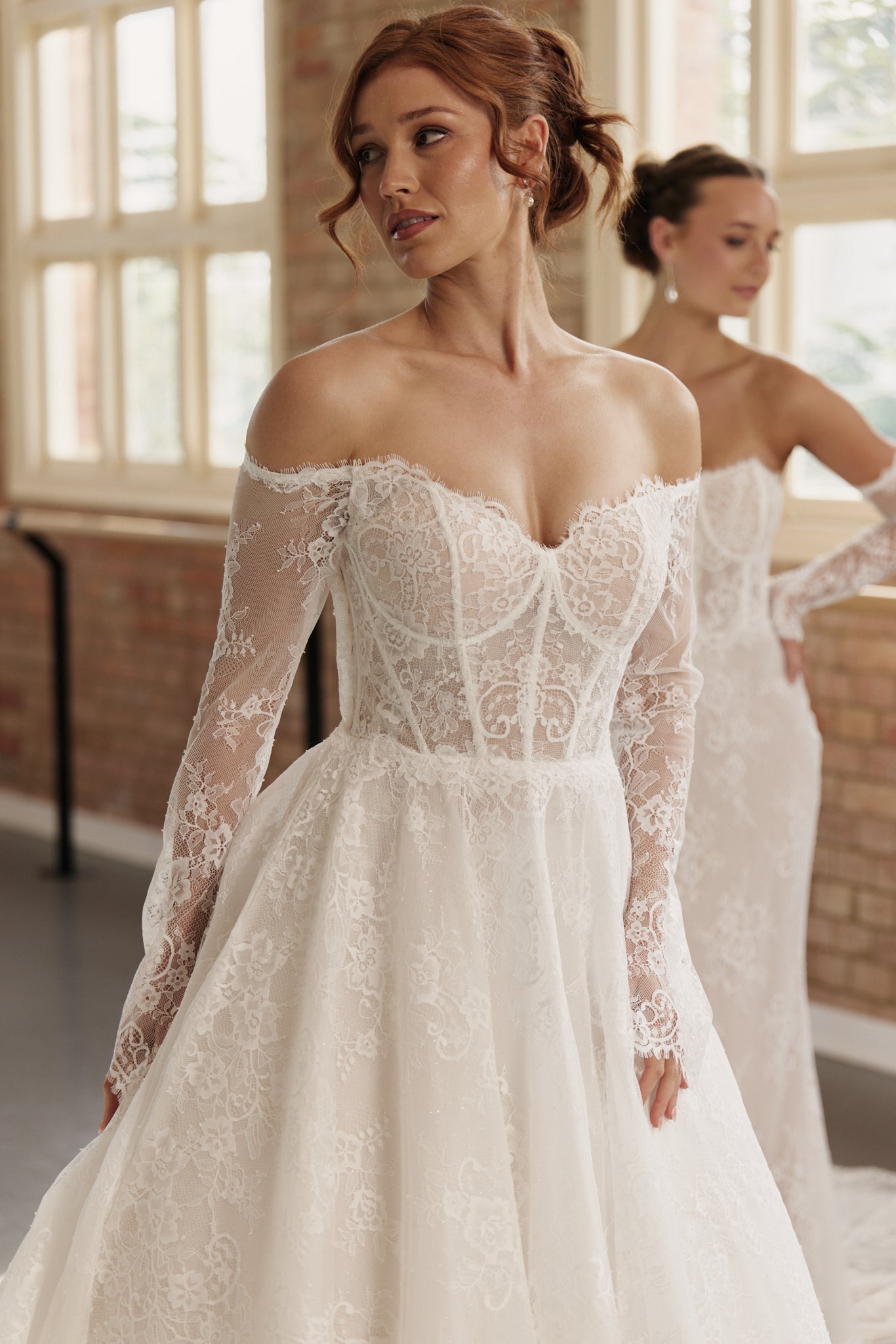 Close-up of corseted lace bodice and off-shoulder long lace sleeves on Elle wedding dress.