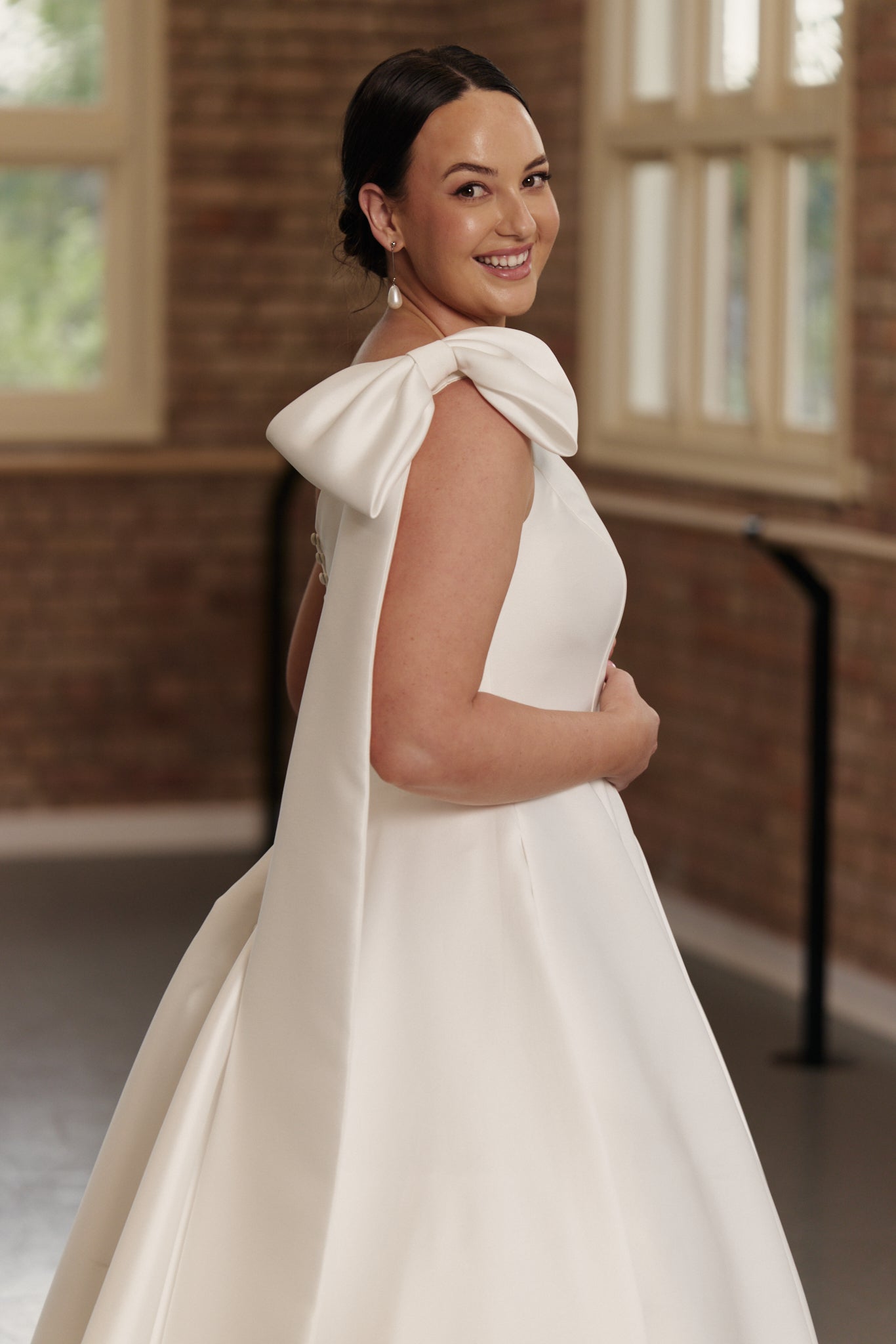 Side profile of the Emily gown highlighting the elegant one-shoulder bow, cinched waist, and voluminous Mikado skirt.
