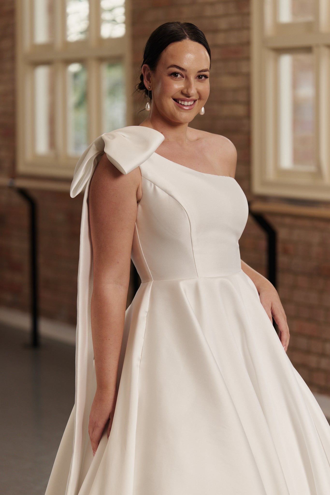 Close-up of the Emily gown’s one-shoulder bow and supportive bodice crafted from glossy Mikado satin.