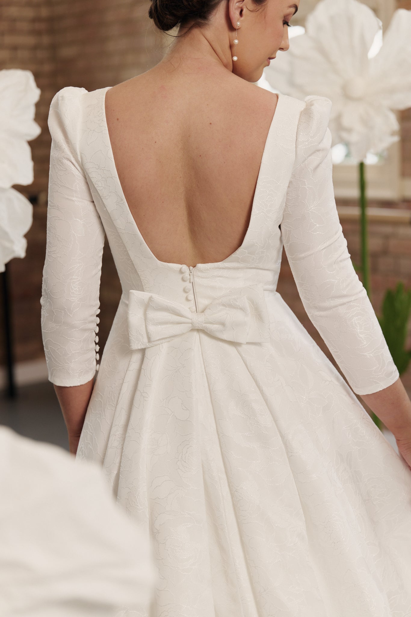 Back of Fleur wedding gown showing open back, 3/4 sleeves in flowing jacquard.