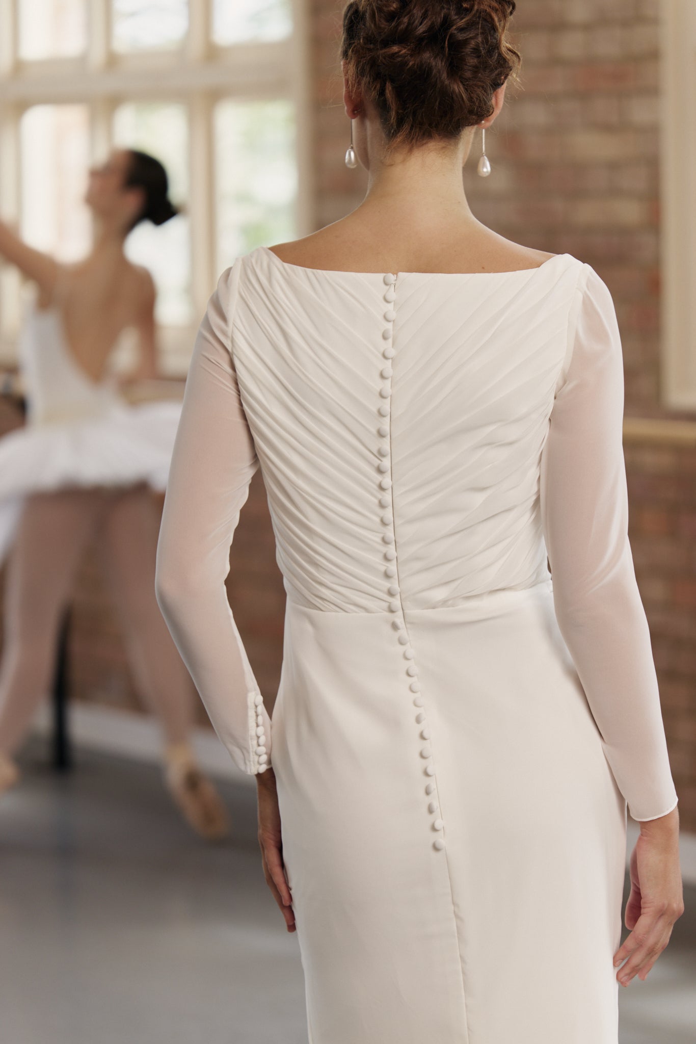 Back of Gigi chiffon sheath wedding dress with long sleeves and ruched, full buttoned back.