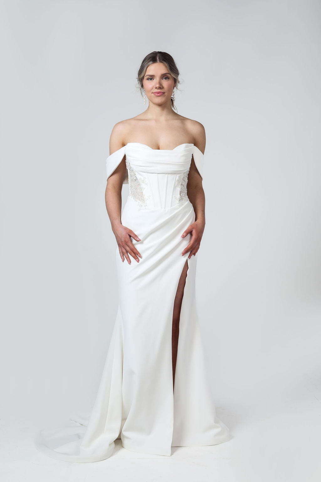 Front view of strapless wedding dress with ruched bodice, exposed boning, beaded detailing, and optional off-the-shoulder sleeves.