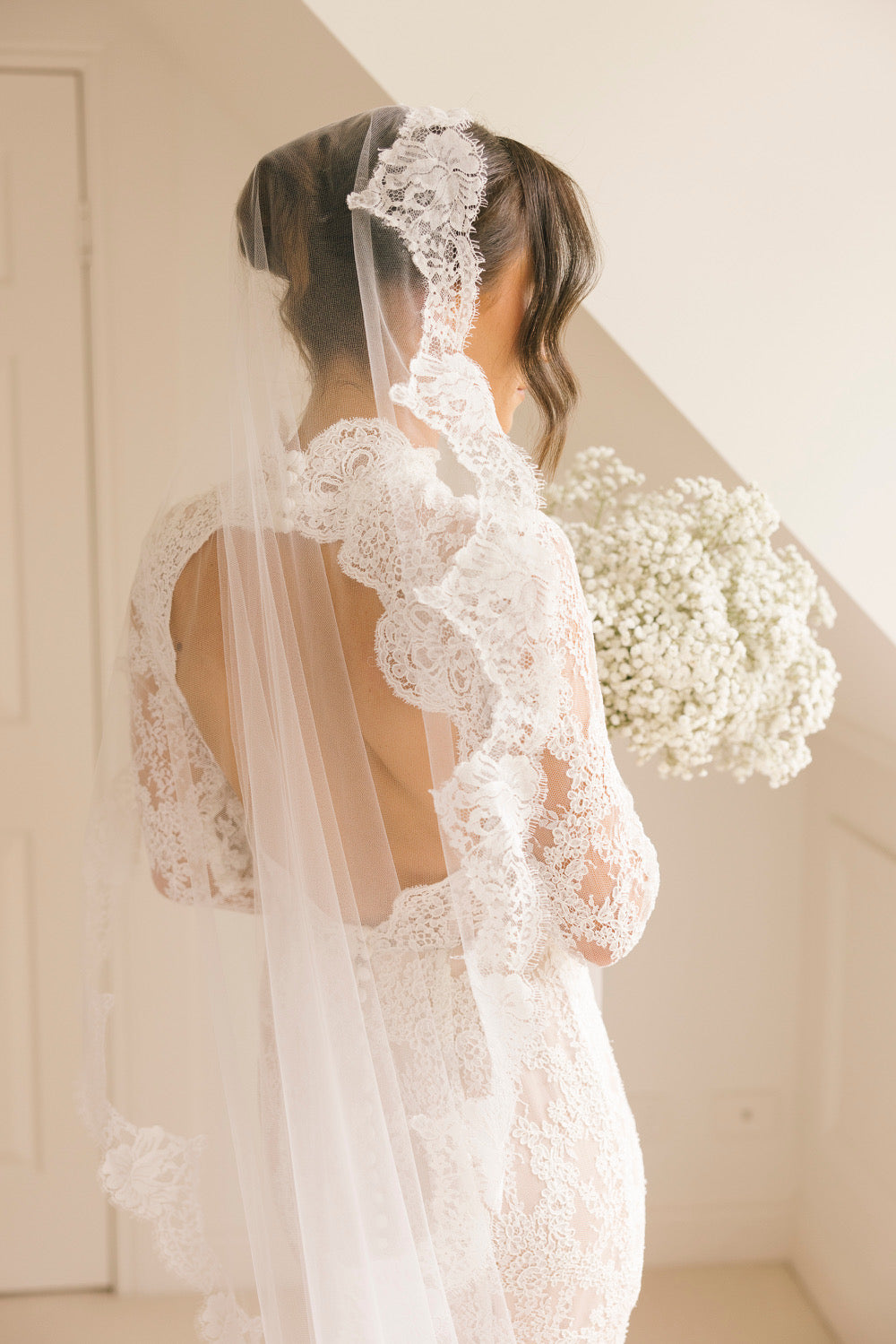 Jess wedding dress with long lace sleeves, high neckline, open back, and fitted silhouette with train