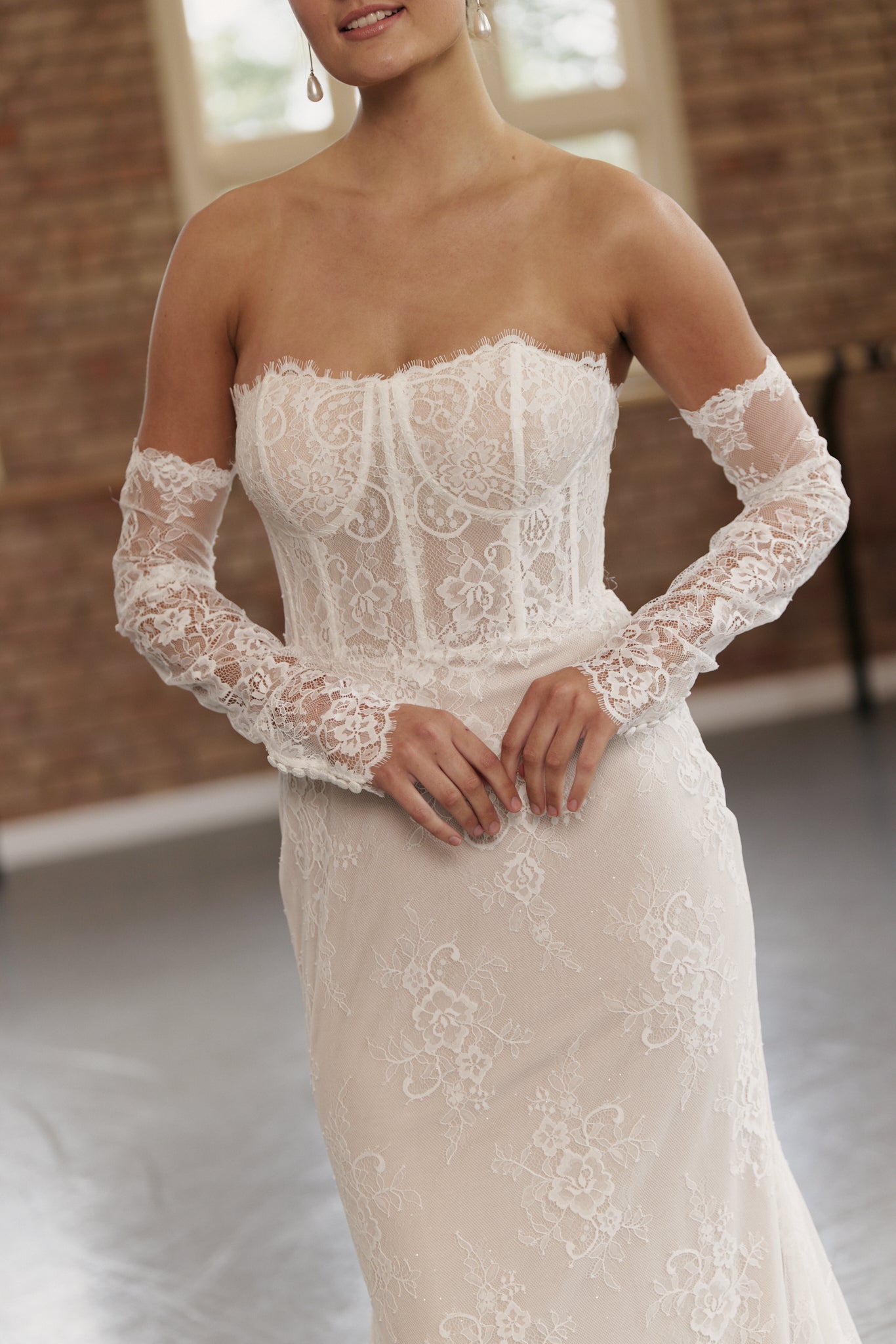 Close-up of corset bodice and lace sleeves on off-the-shoulder lace wedding dress.