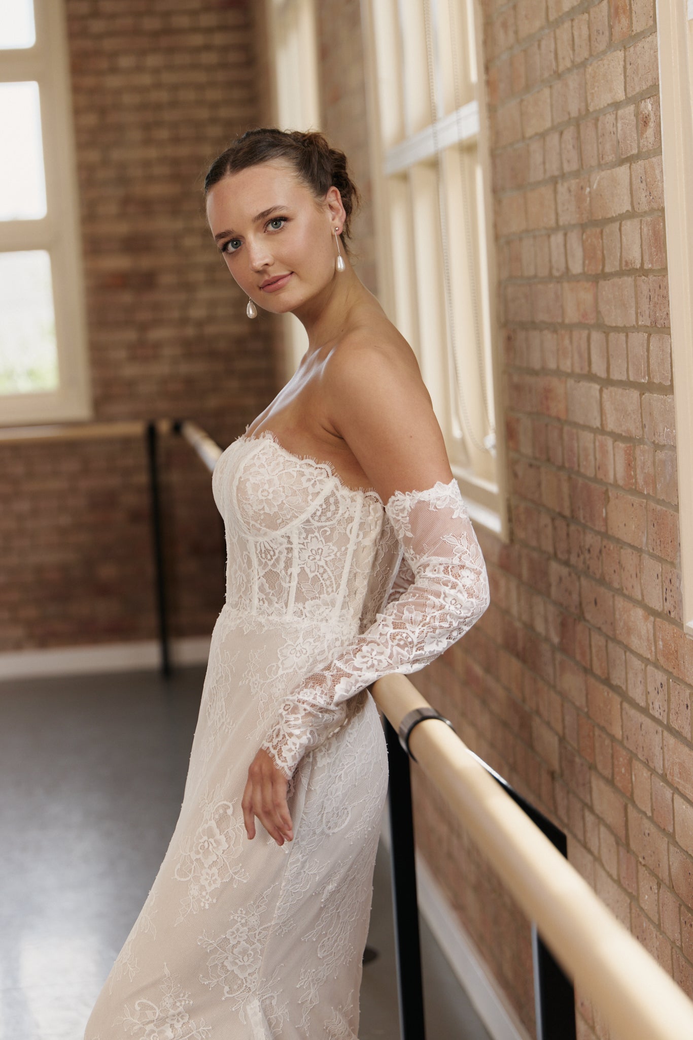 Side view of off-the-shoulder lace wedding gown with long sleeves and figure-flattering mermaid silhouette.