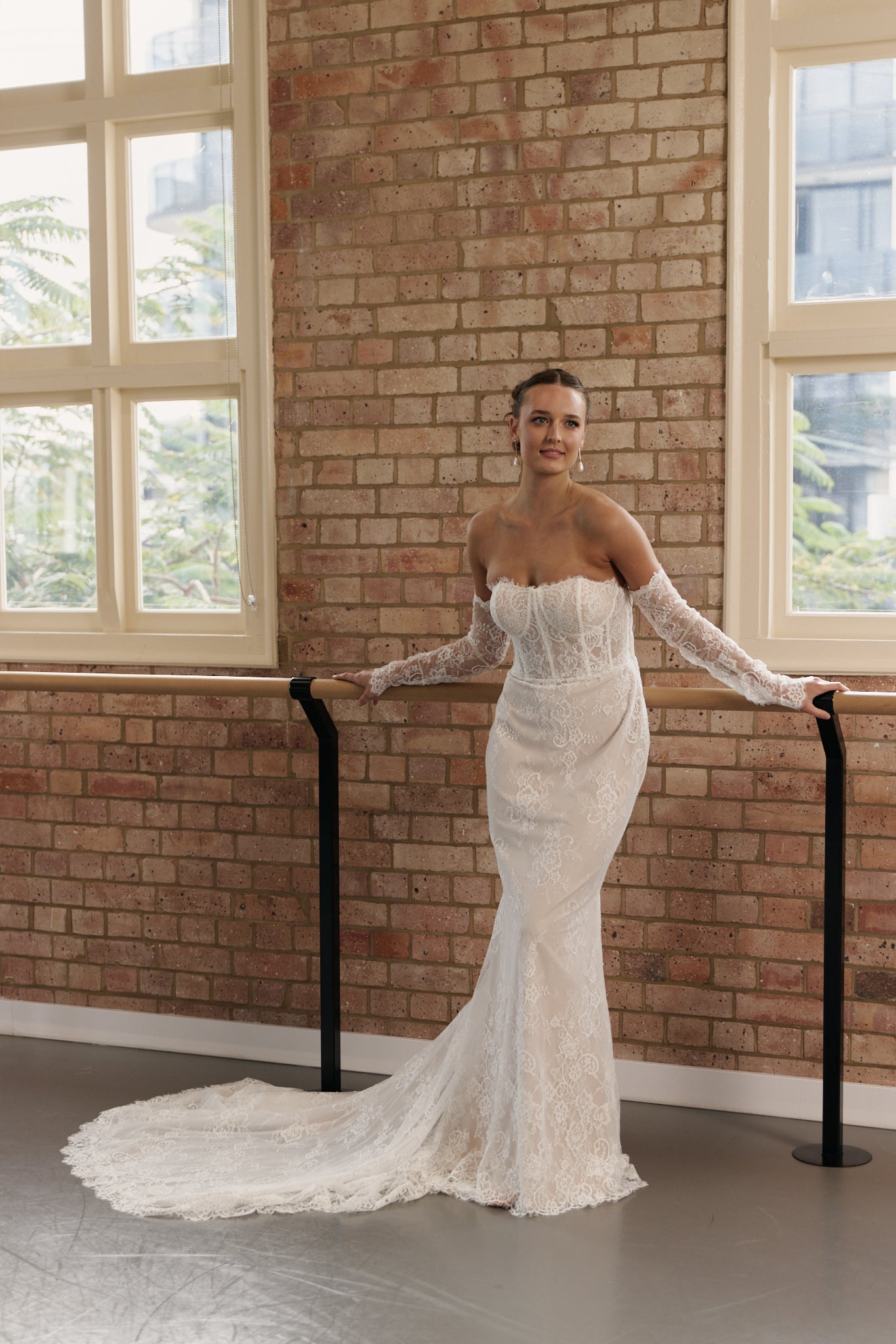 Bride wearing off-the-shoulder lace wedding dress with long sleeves, structured corset bodice, and mermaid silhouette