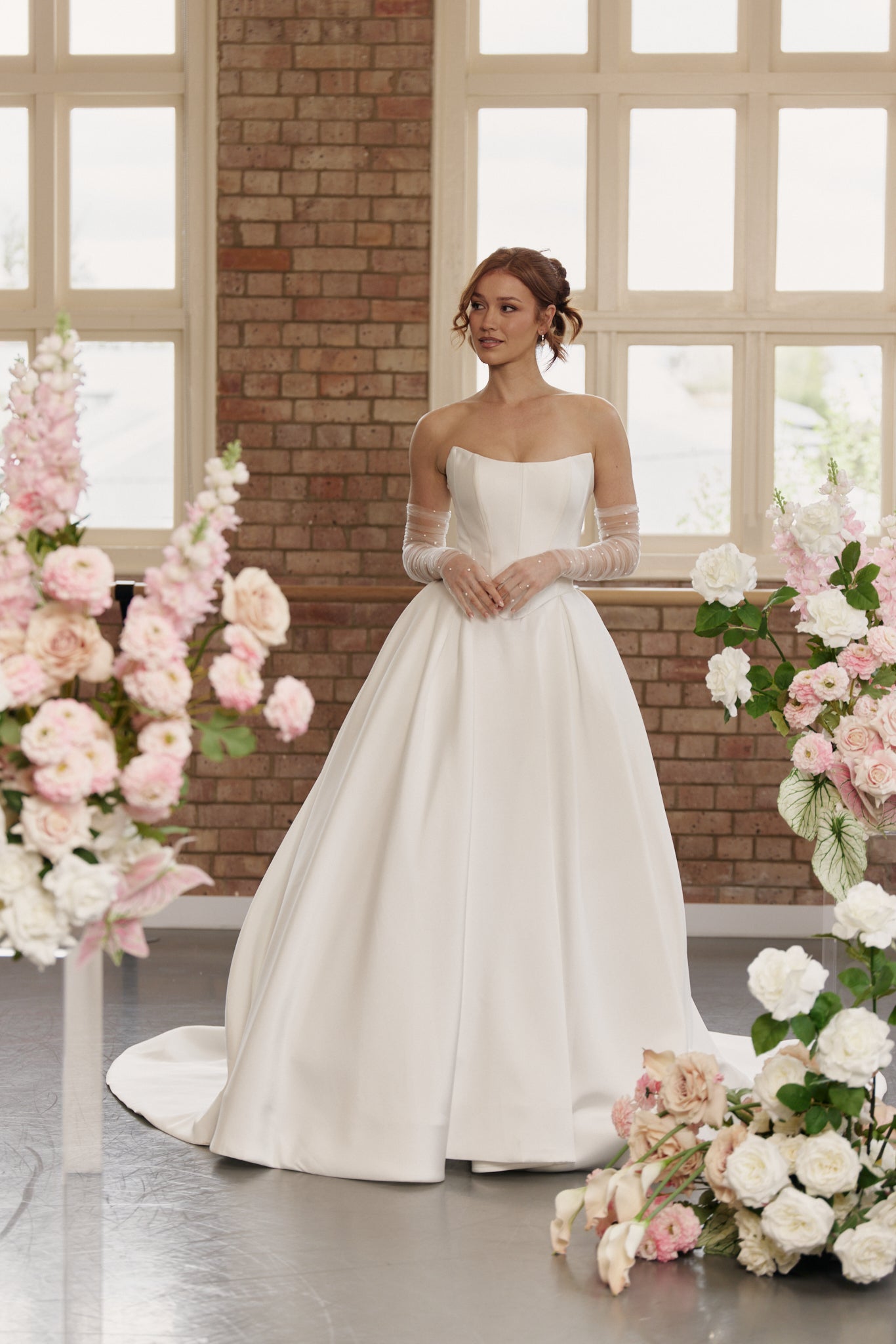 The Mackenzie strapless wedding dress with a sculpted corset bodice, basque waist, and elegant princess ball gown skirt.