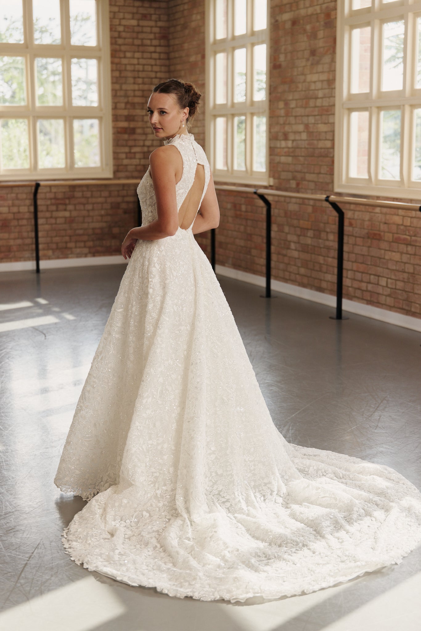 Back view of the Mia bridal dress showing the open back detail, shimmering beaded fabric, and voluminous princess-style skirt.