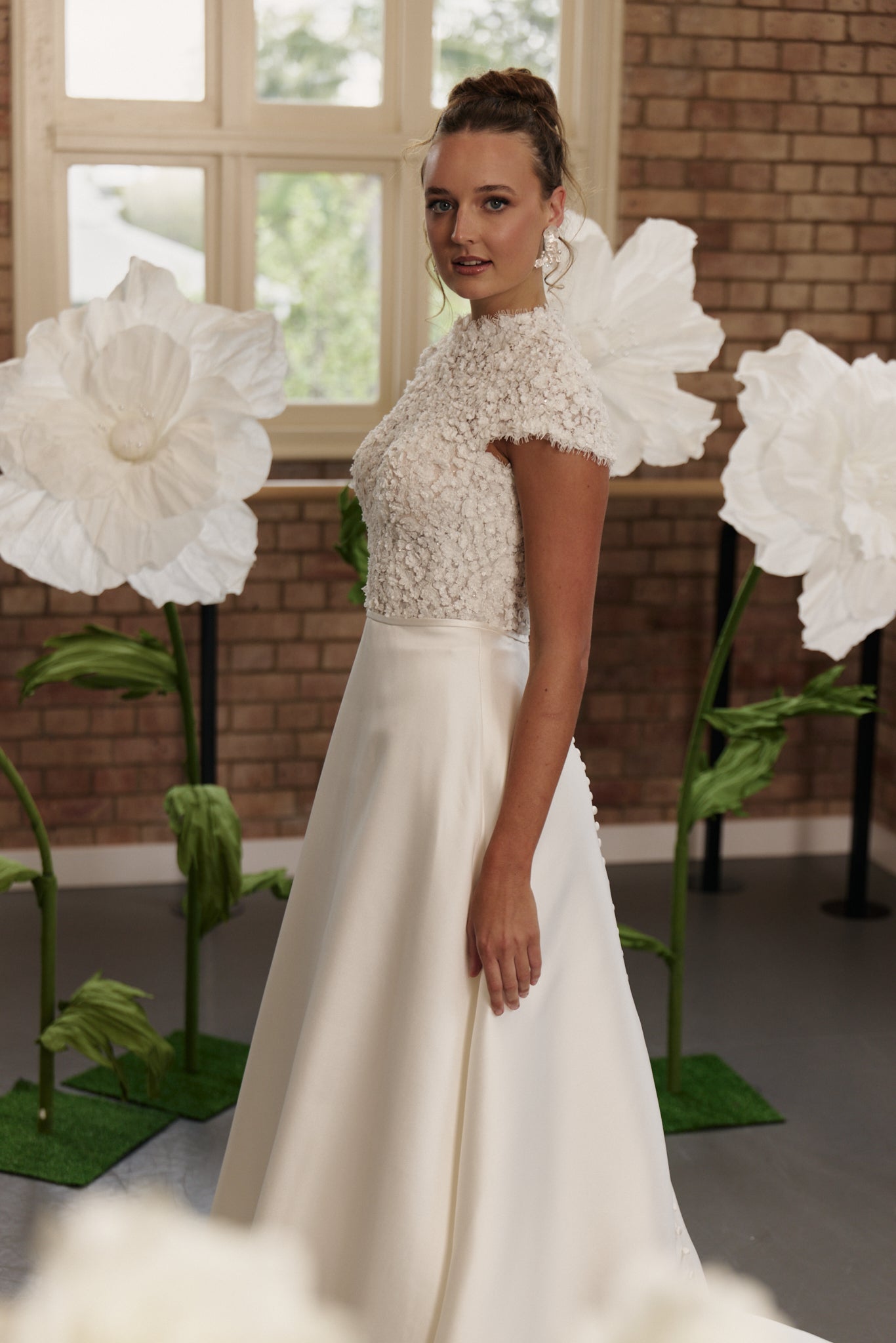 Side profile of classic wedding dress highlighting floral lace bodice, cap sleeves, and elegant A-line silhouette.