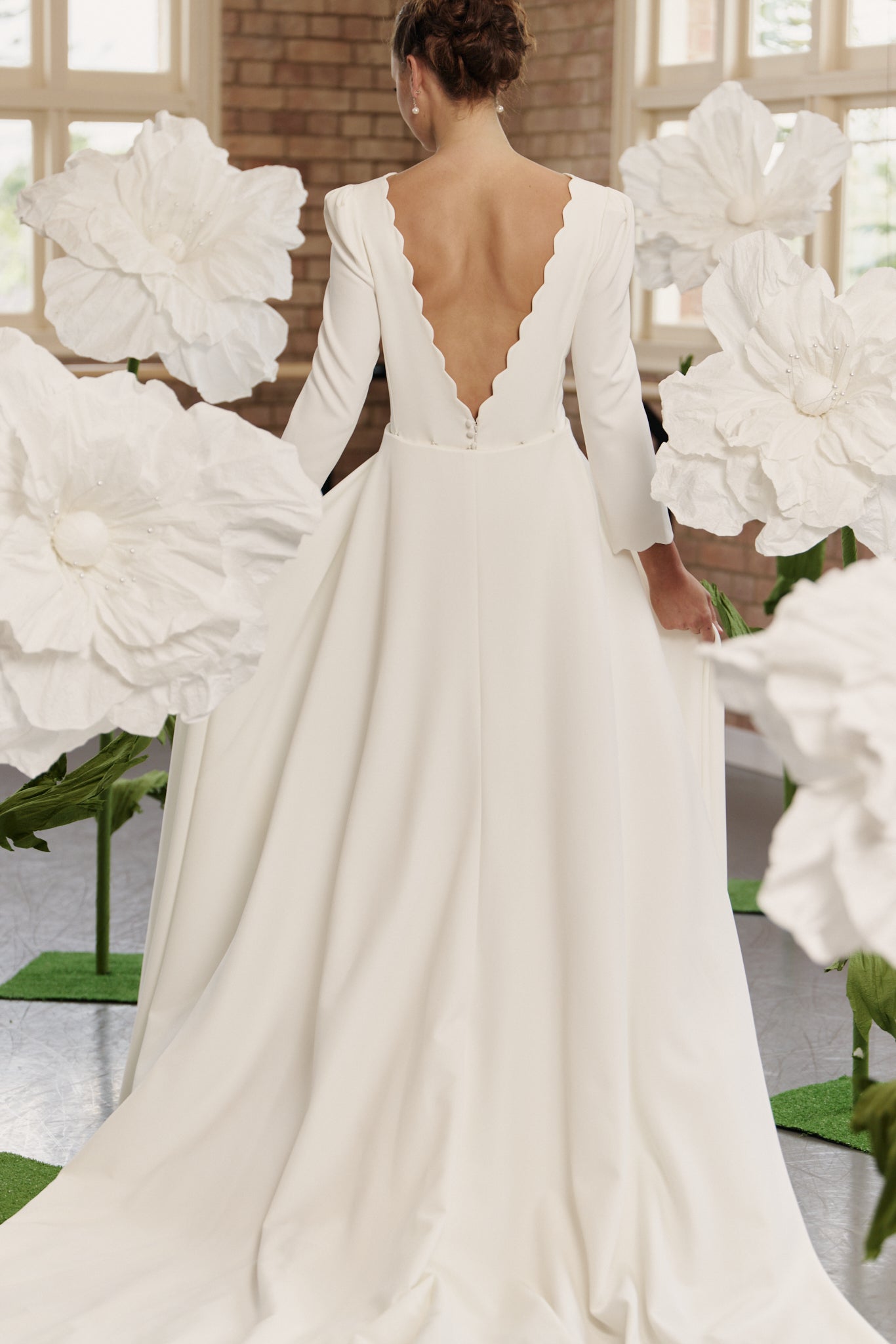Back view of the Shari bridal gown showcasing low back, optional overskirt, and dramatic full train