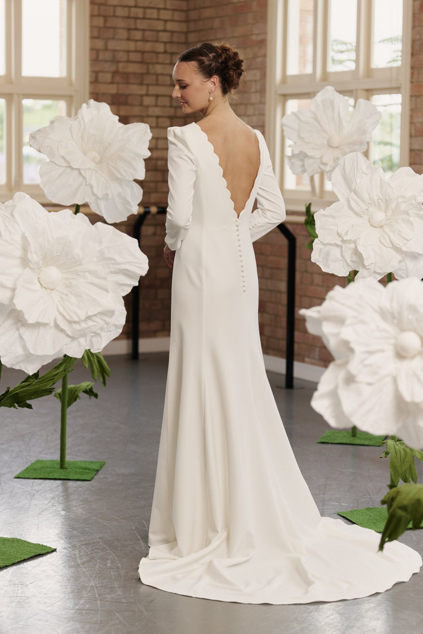 Back view of the Shari bridal gown showcasing low back, optional overskirt, and dramatic full train