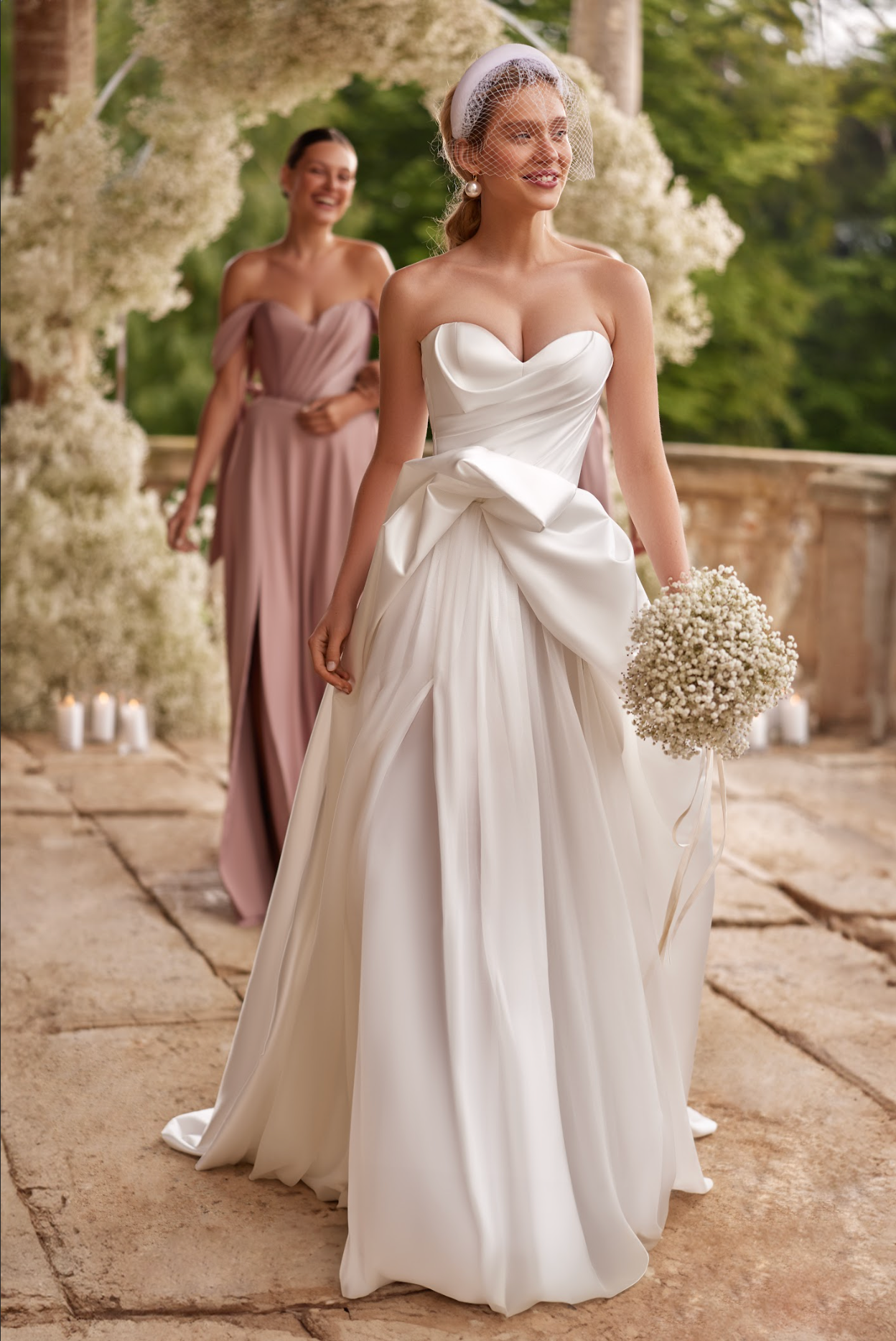 Sofi Wedding Gown, with satin corset, a-line silhouette, long skirt with split and train, ruched bodice, strapless with sweetheart neckline, ruffle detail around skirt top.