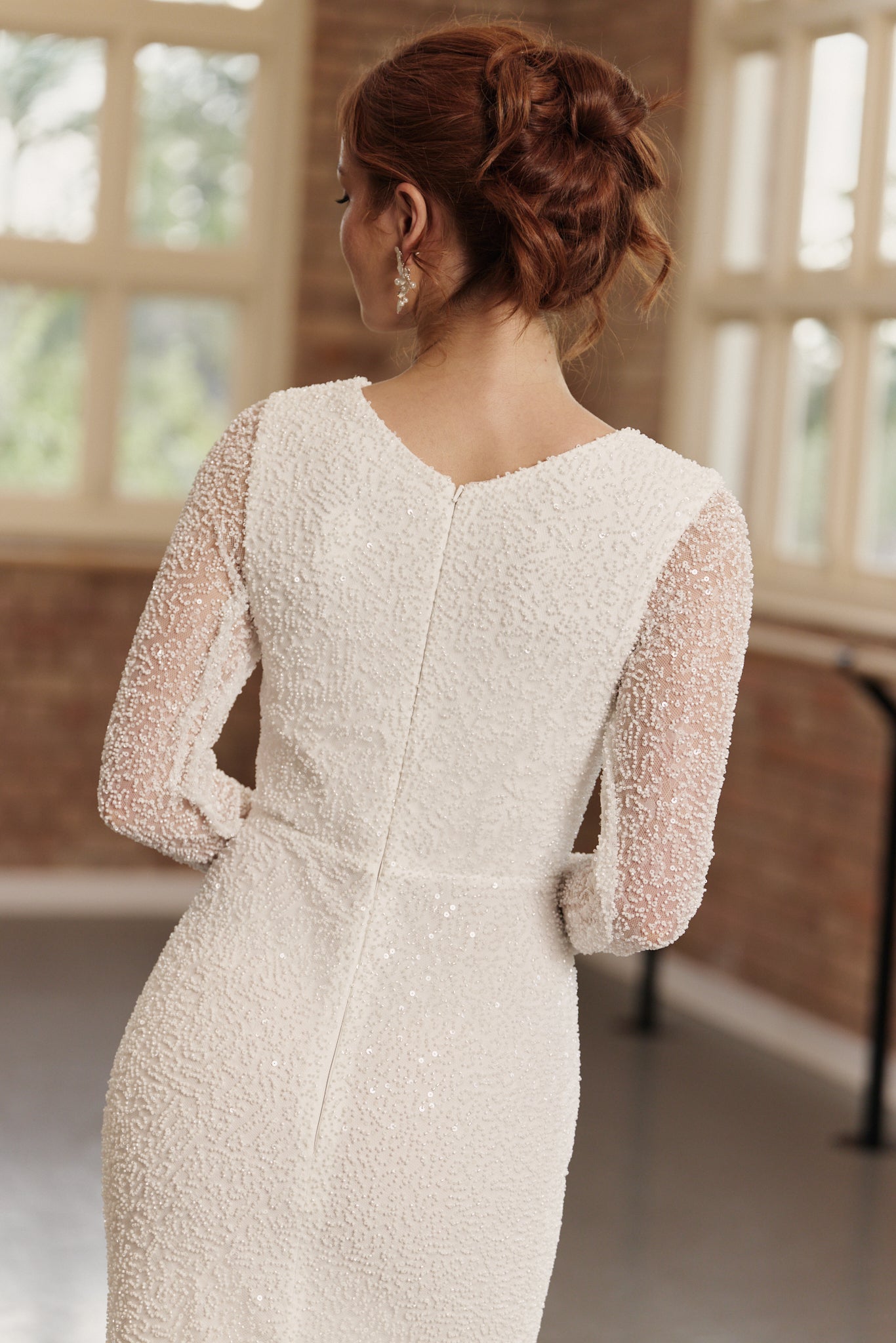 High back of Kelsey wedding dress showing long sleeves, boat neck, beaded design, and mermaid skirt.