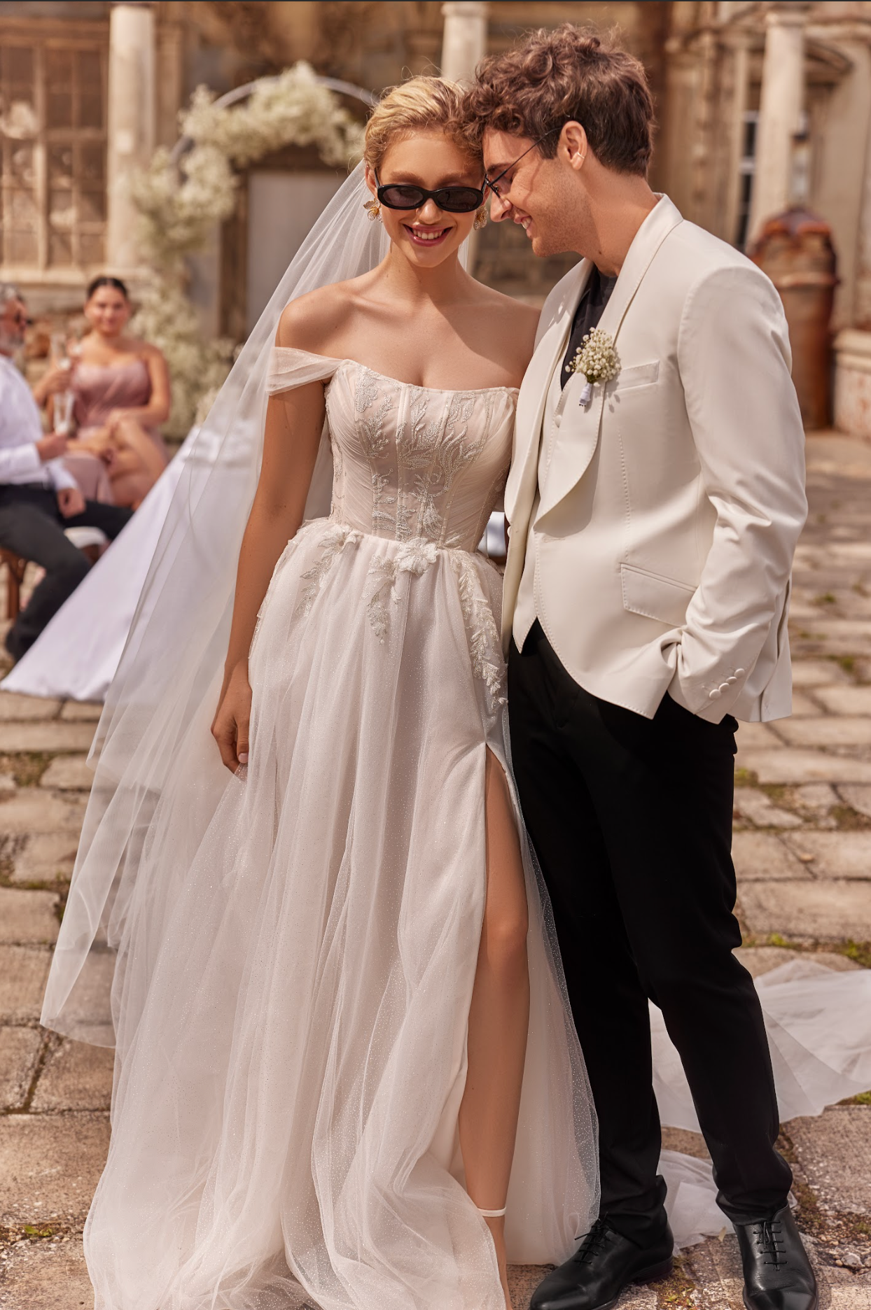 Vesta Wedding Gown, corset bodice with pleated ruching across bodice, flowy tulle skirt, detachable long sleeves, sweetheart neckline, strapless, delicate bow at waist.