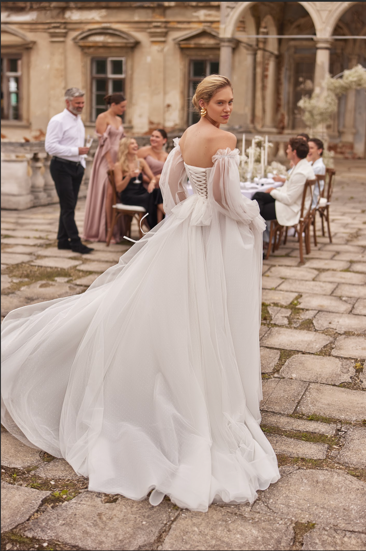 Vesta Wedding Gown, corset bodice with pleated ruching across bodice, flowy tulle skirt, detachable long sleeves, sweetheart neckline, strapless, delicate bow at waist.